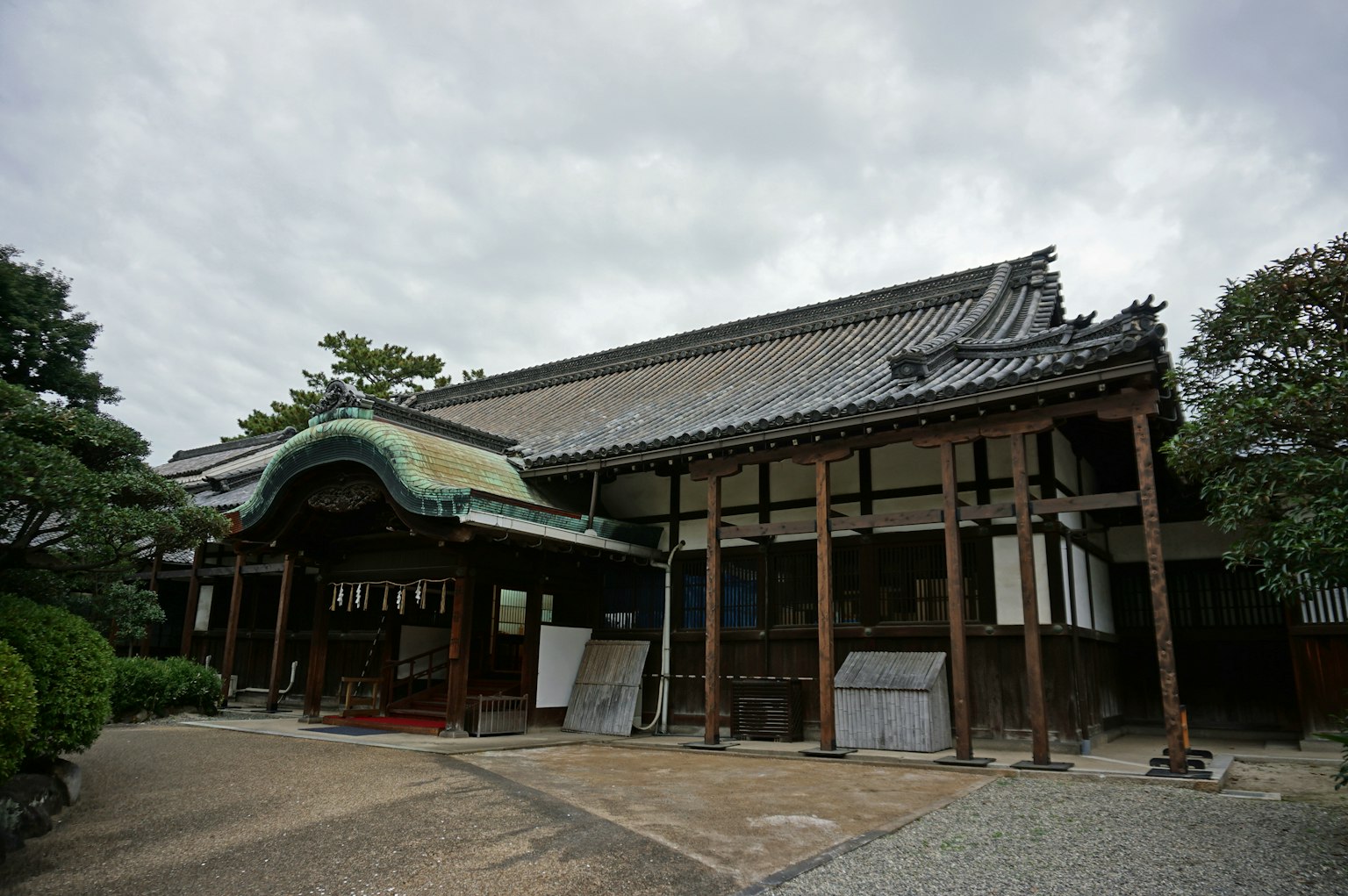Extérieur d'un ancien bâtiment japonais avec un toit vert et des piliers en bois