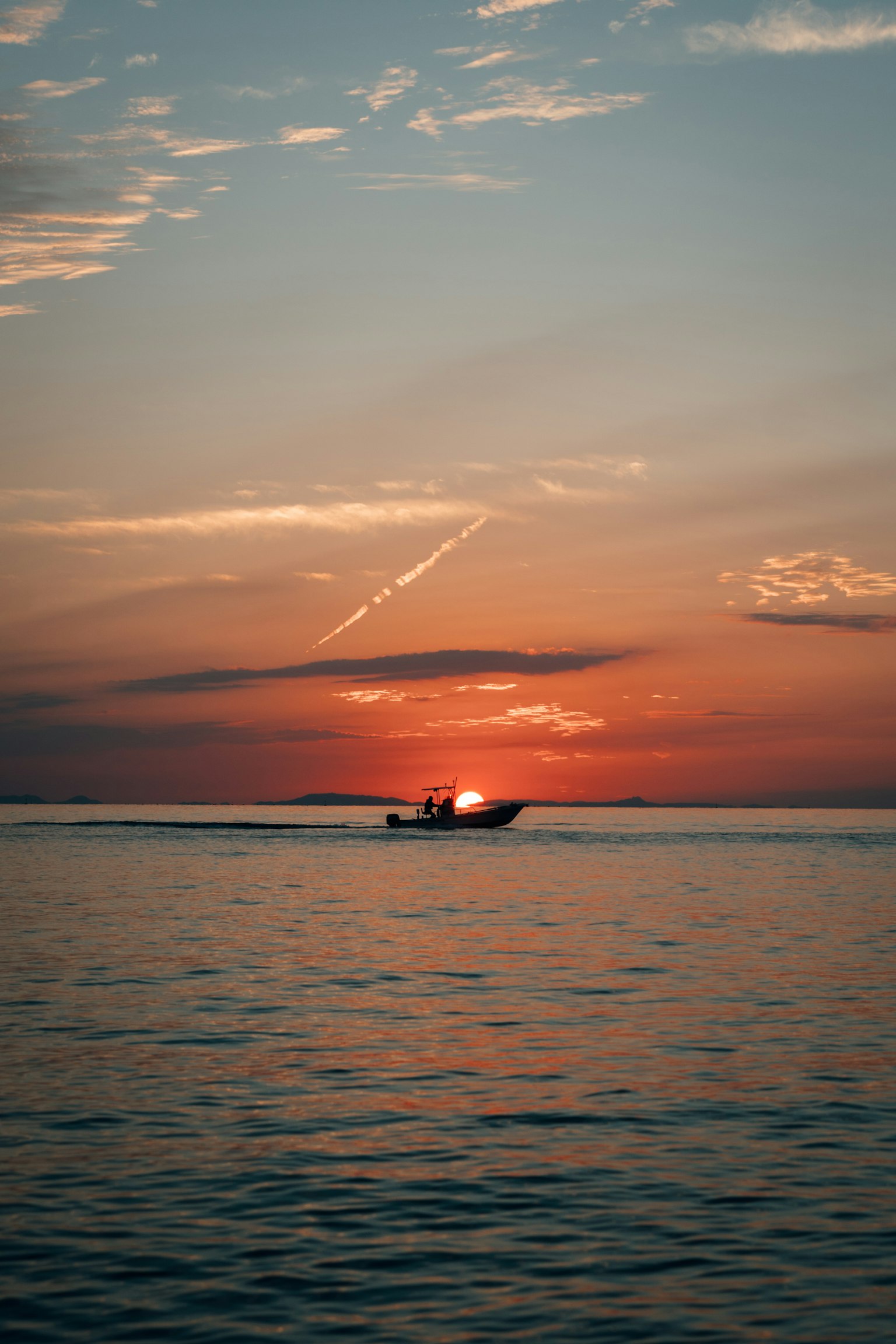 Un petit bateau dérivant sur l'eau avec le coucher de soleil en arrière-plan