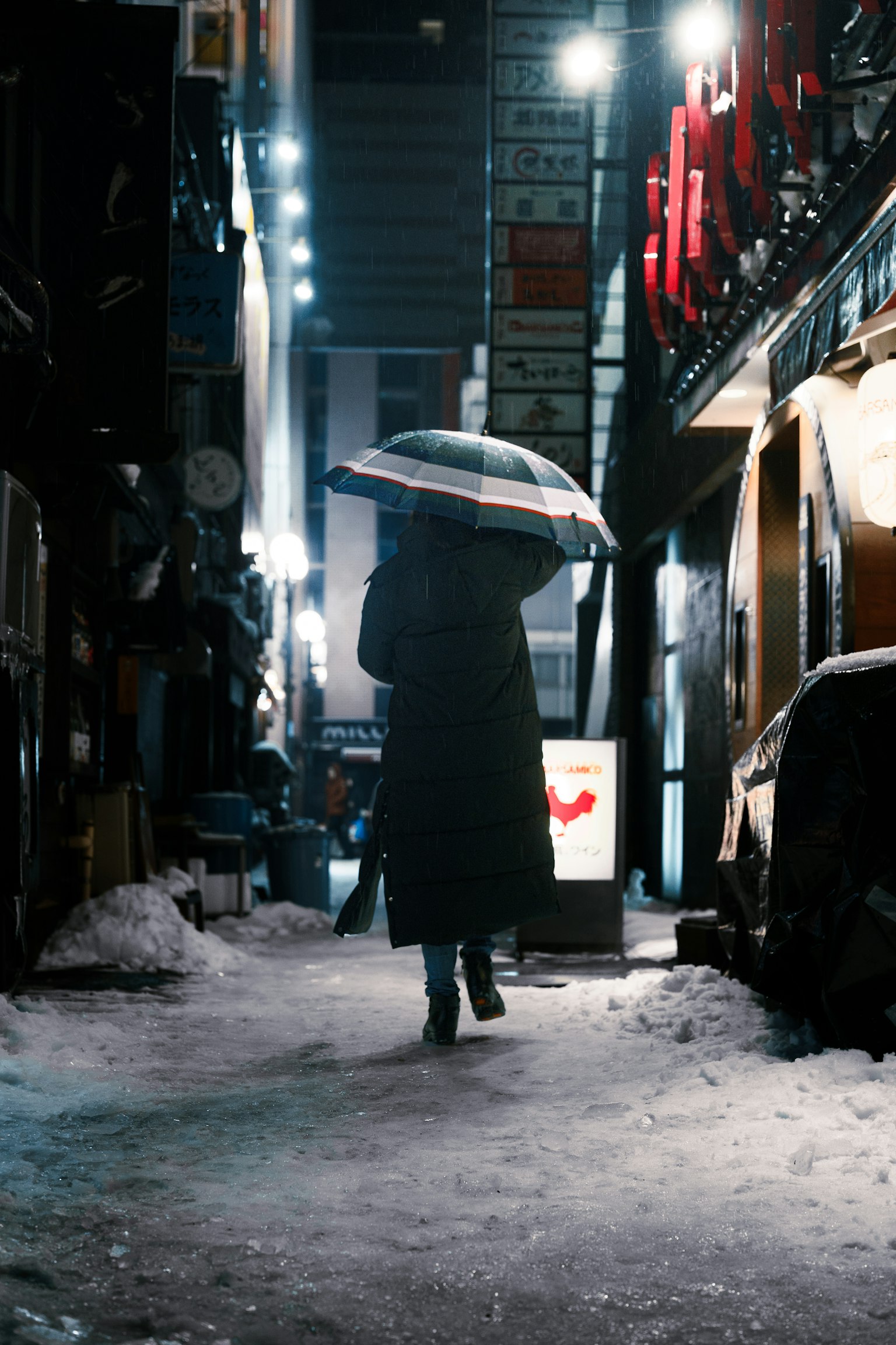 在雪中撐著傘走的人  昏暗的小巷中散落著燈光