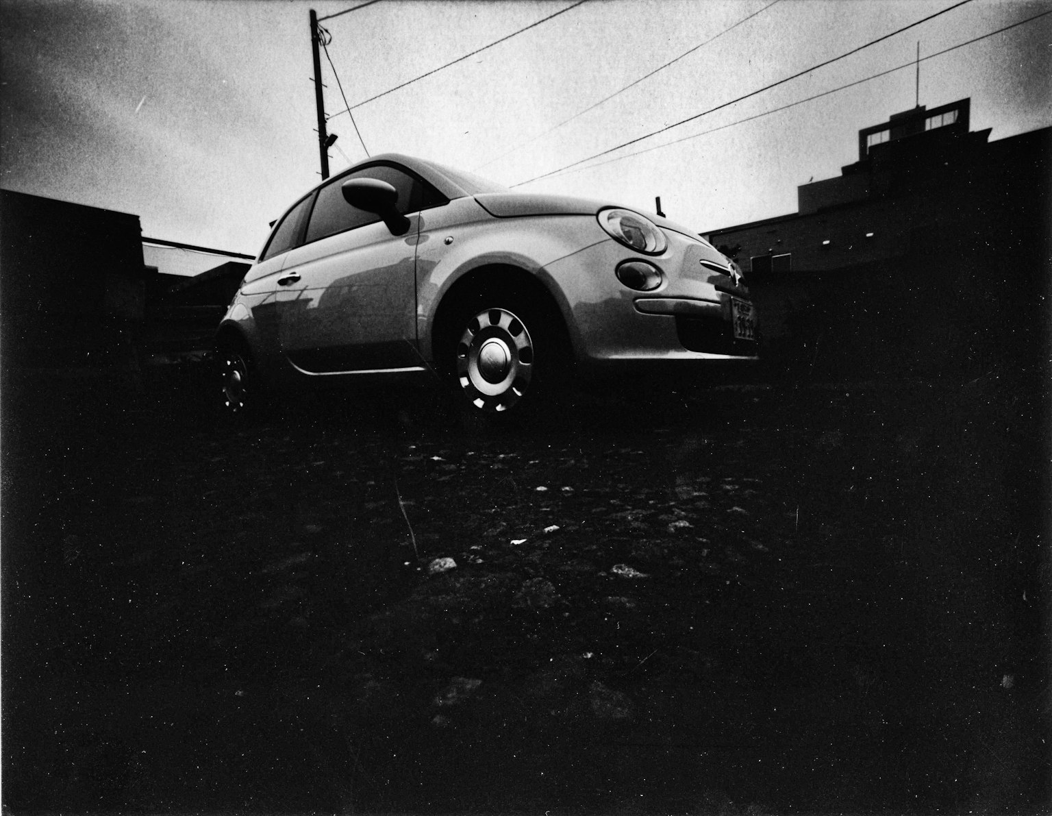Black and white photo of a Fiat 500 parked against a dark background