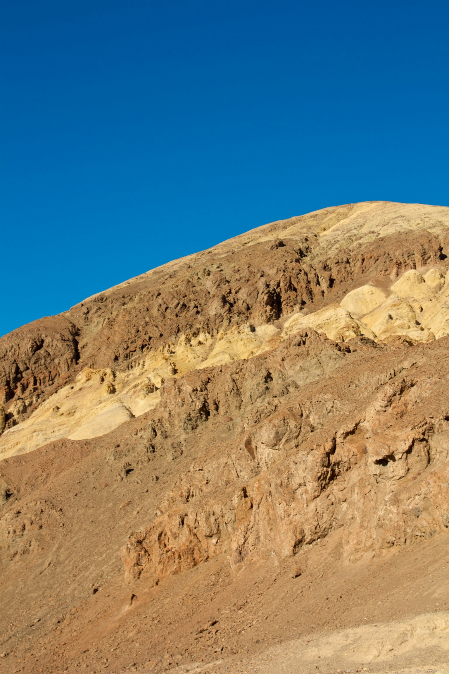Montaña marrón estratificada bajo un cielo azul claro