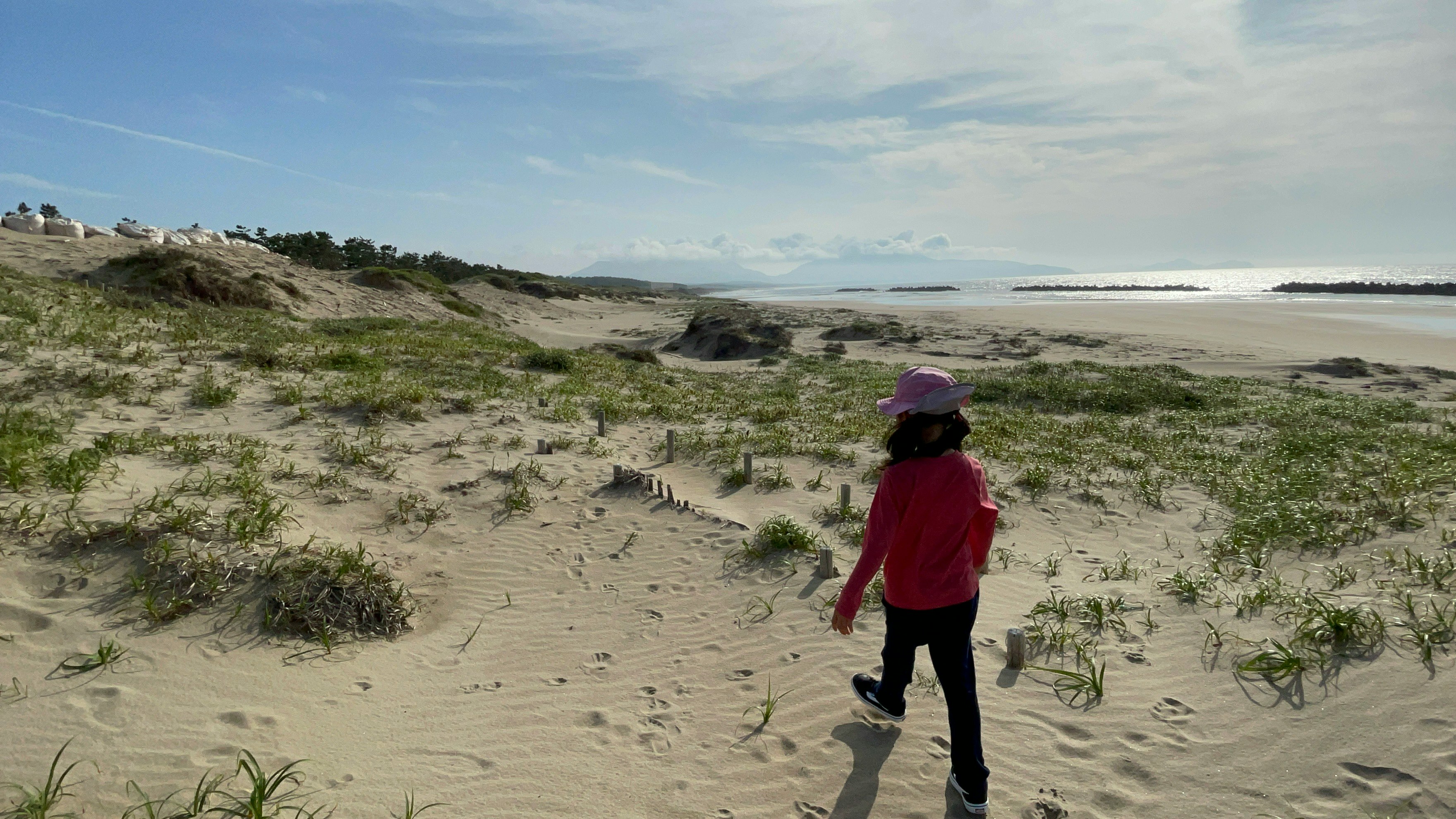 Eine Person geht am Sandstrand am Meer entlang