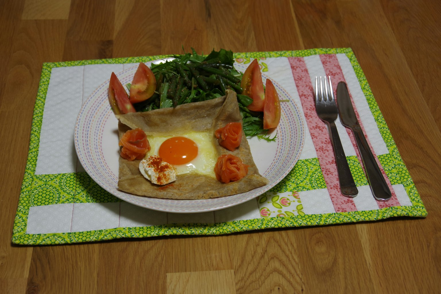 Un piatto di galette con uovo e pomodori servito con insalata verde