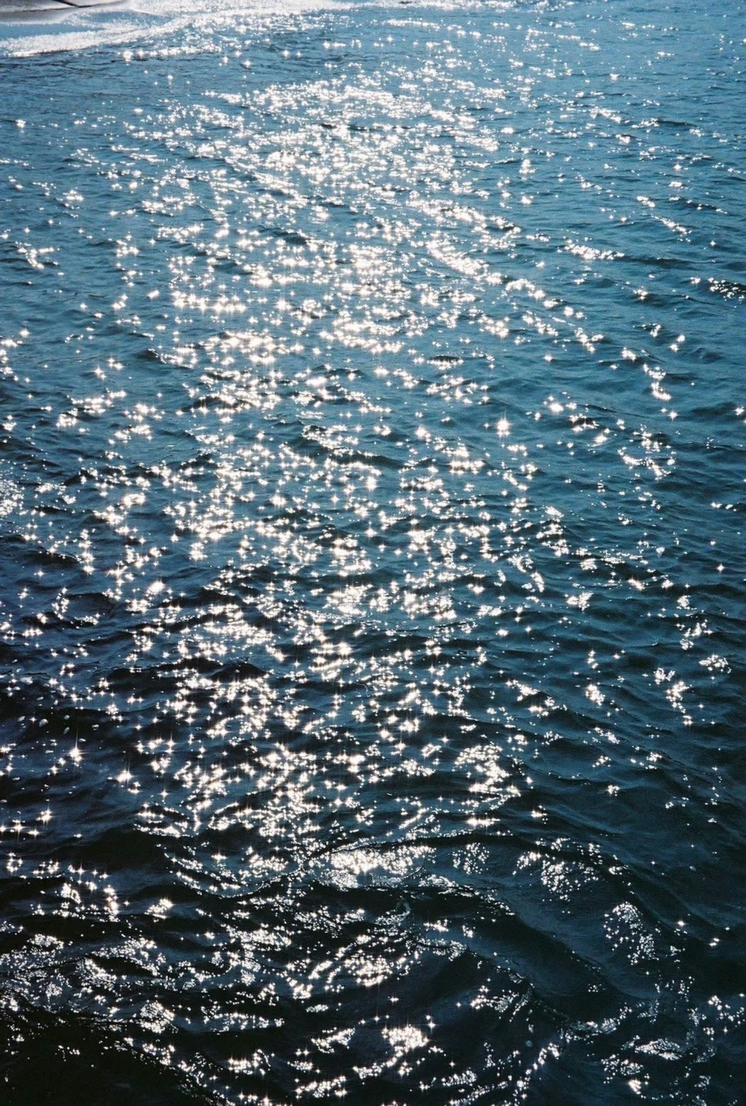 水面に反射する光の輝きが美しい青い海の画像