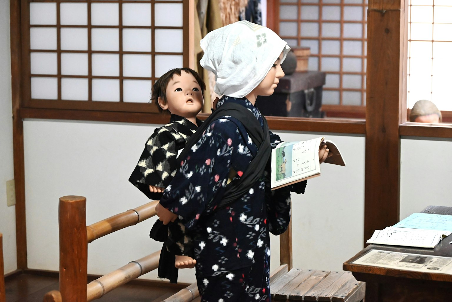 一個穿著傳統服裝的孩子在木屋裡背著一個嬰兒