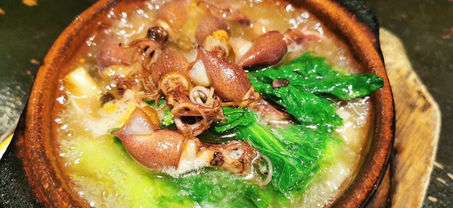 Plato de mariscos cocido en una olla con verduras verdes