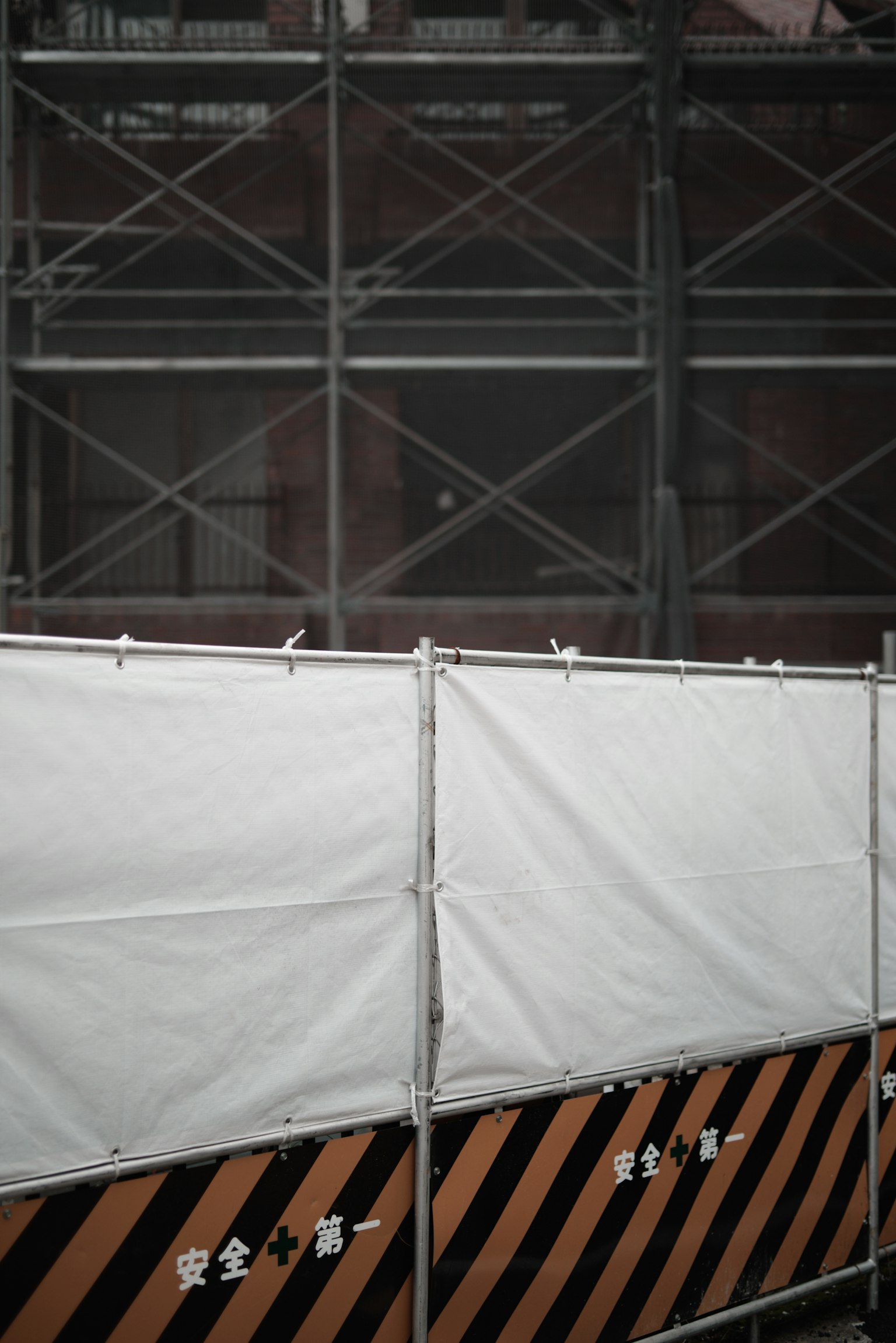 Chantier avec une toile blanche et une barricade rayée noire et orange