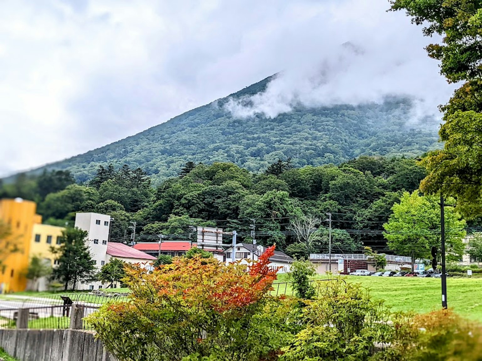 Scenic view of a lush green mountain with a cloudy peak in the background