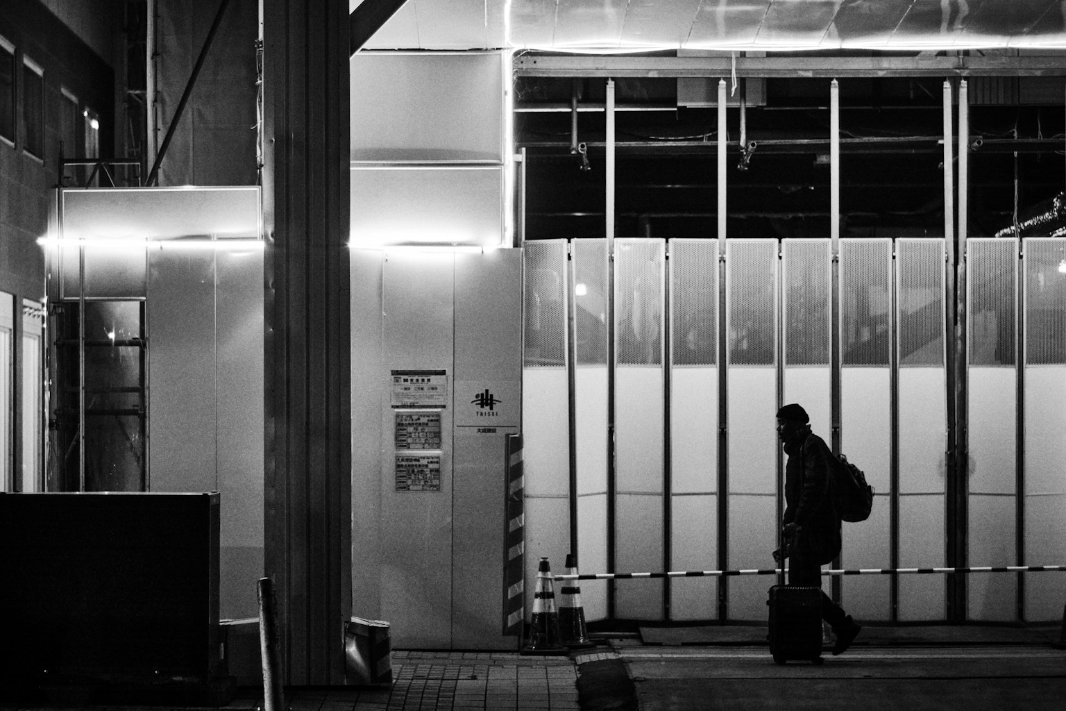 Una persona caminando de noche junto a un edificio iluminado