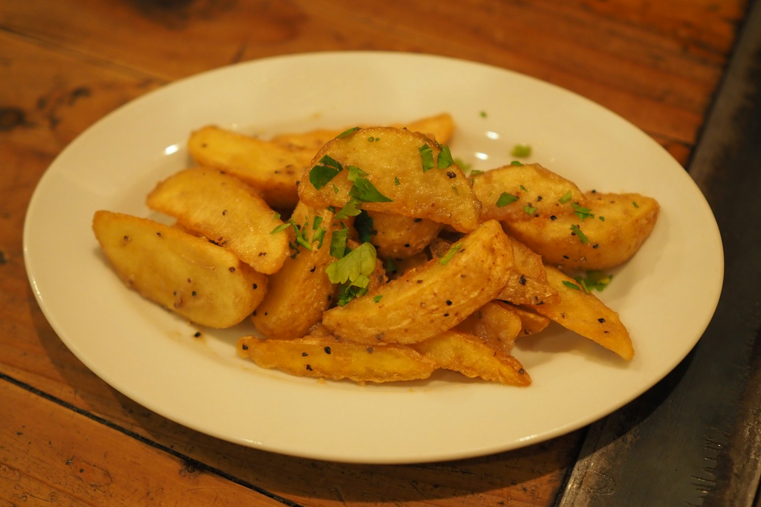 Herb-topped potato wedges served on a white plate