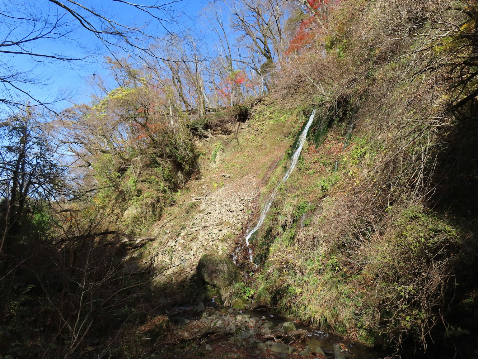Collina rigogliosa con una piccola cascata sotto un cielo blu