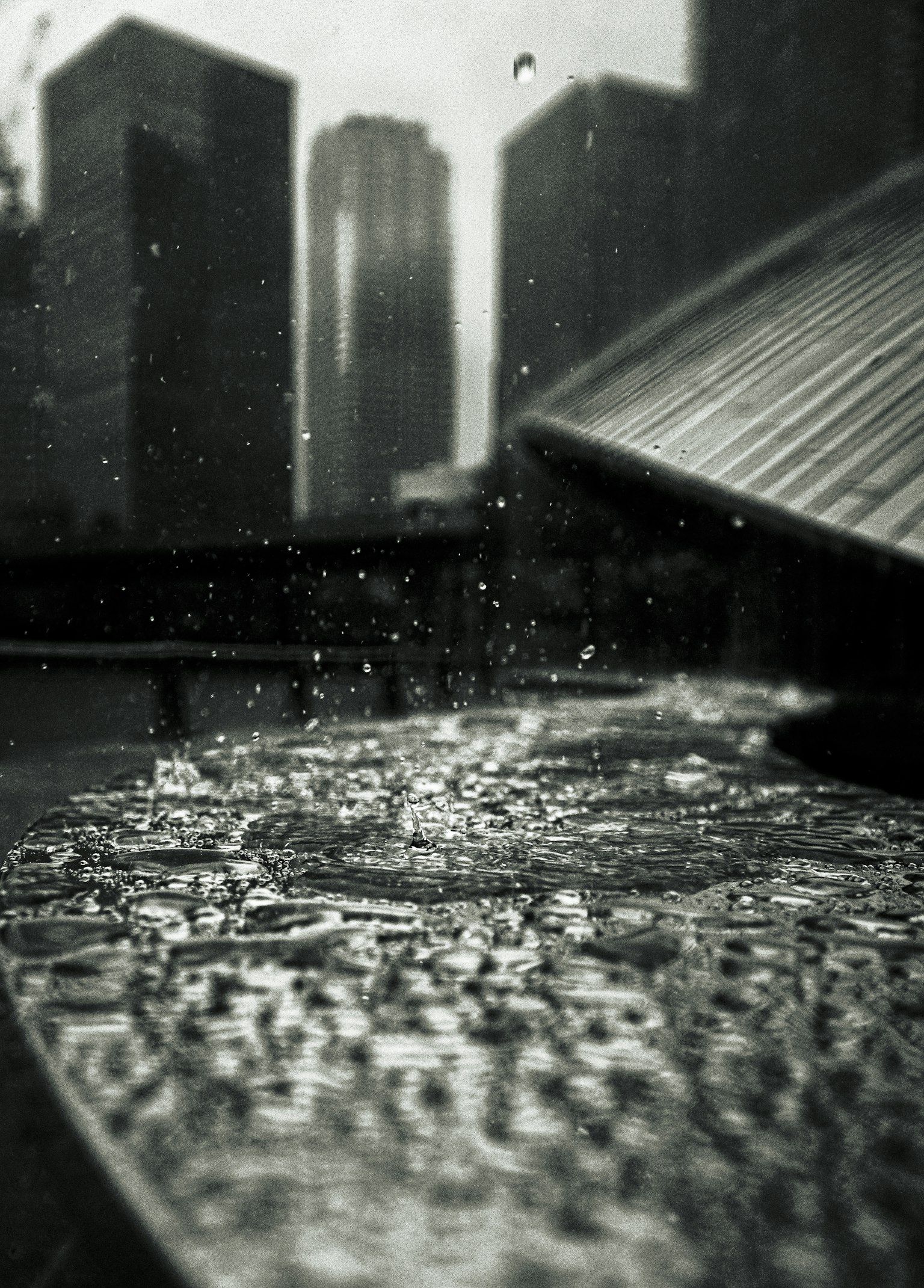 Gouttes de pluie tombant sur une surface avec une ville en arrière-plan monochrome