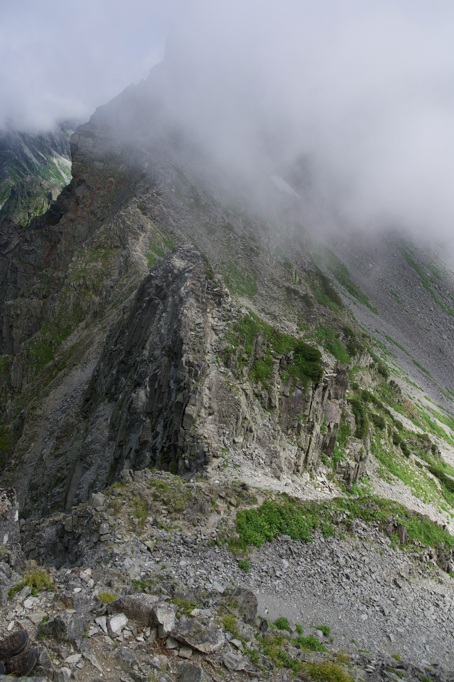 被霧籠罩的山景，陡峭的懸崖和綠色植被