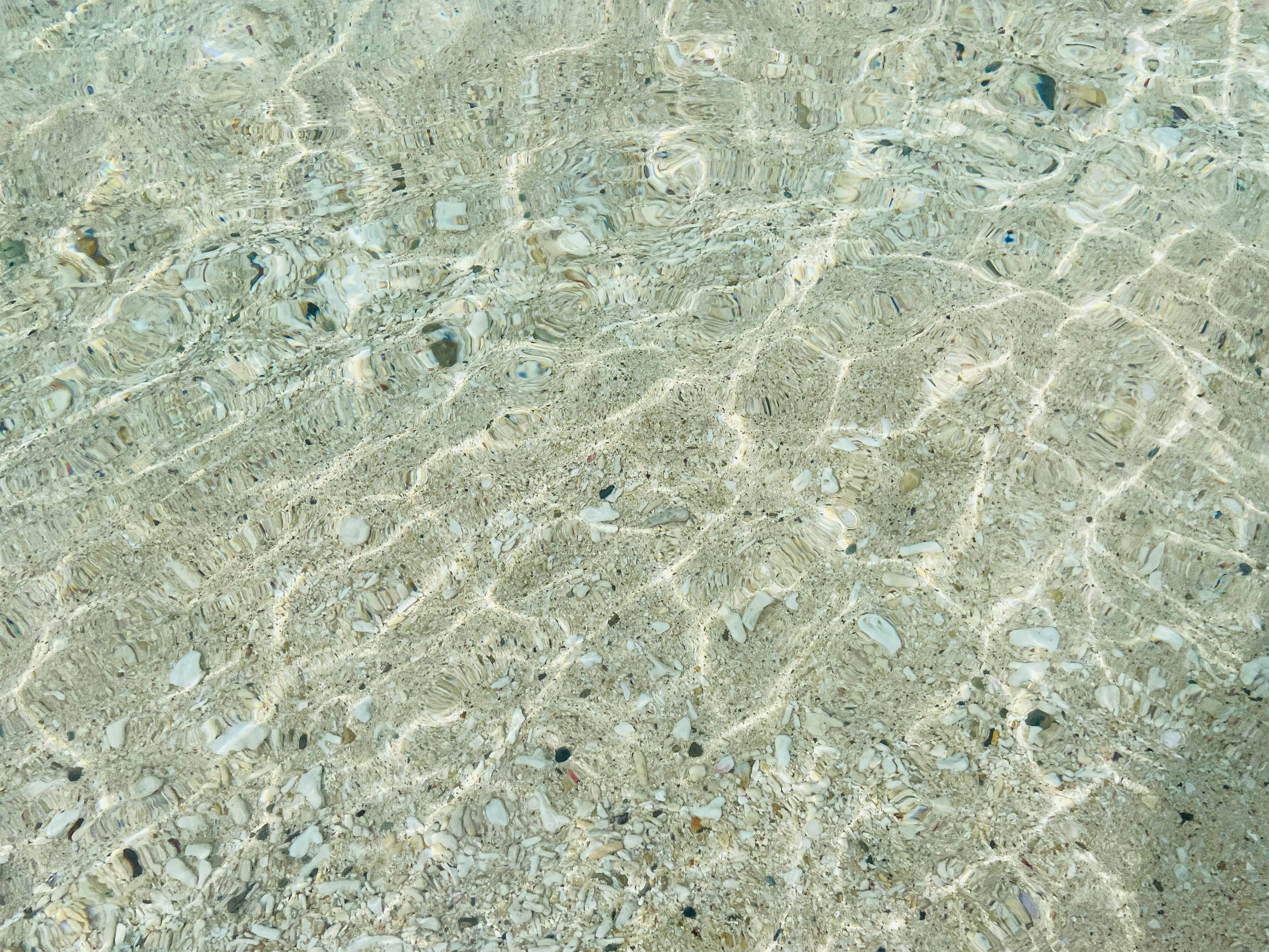 Klare Wasseroberfläche, die den sandigen Boden in einer schönen Strandumgebung widerspiegelt