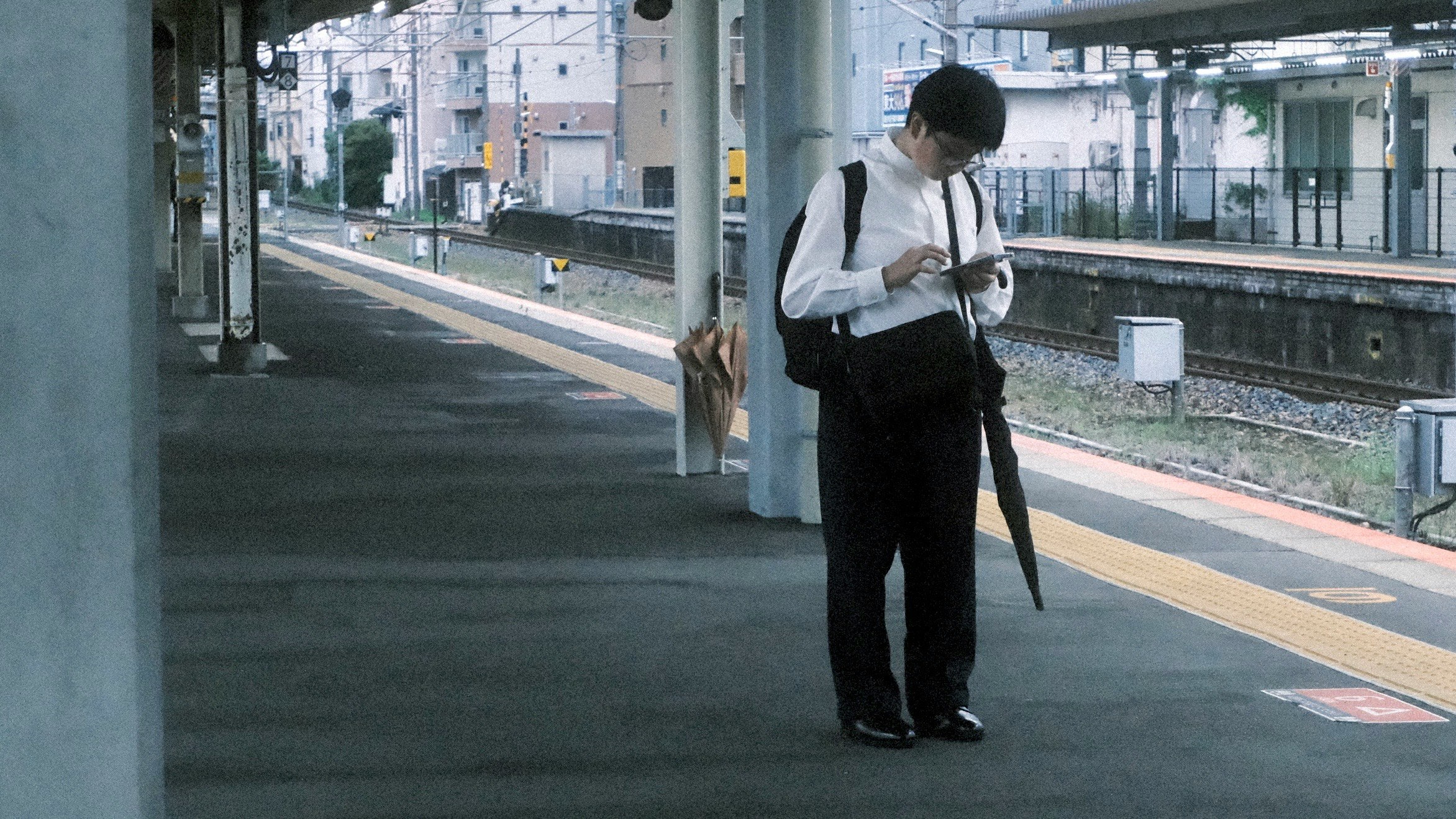 高架下の通路で立つスーツ姿の人物