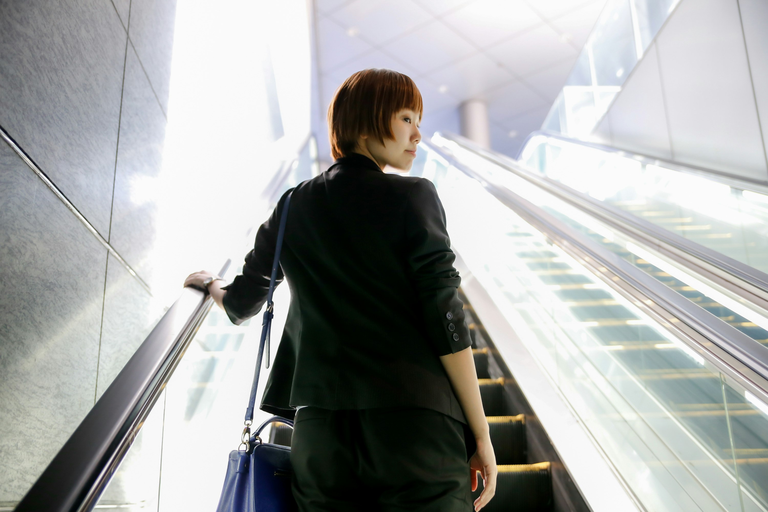 駅の通路で階段を上がる女性の後ろ姿