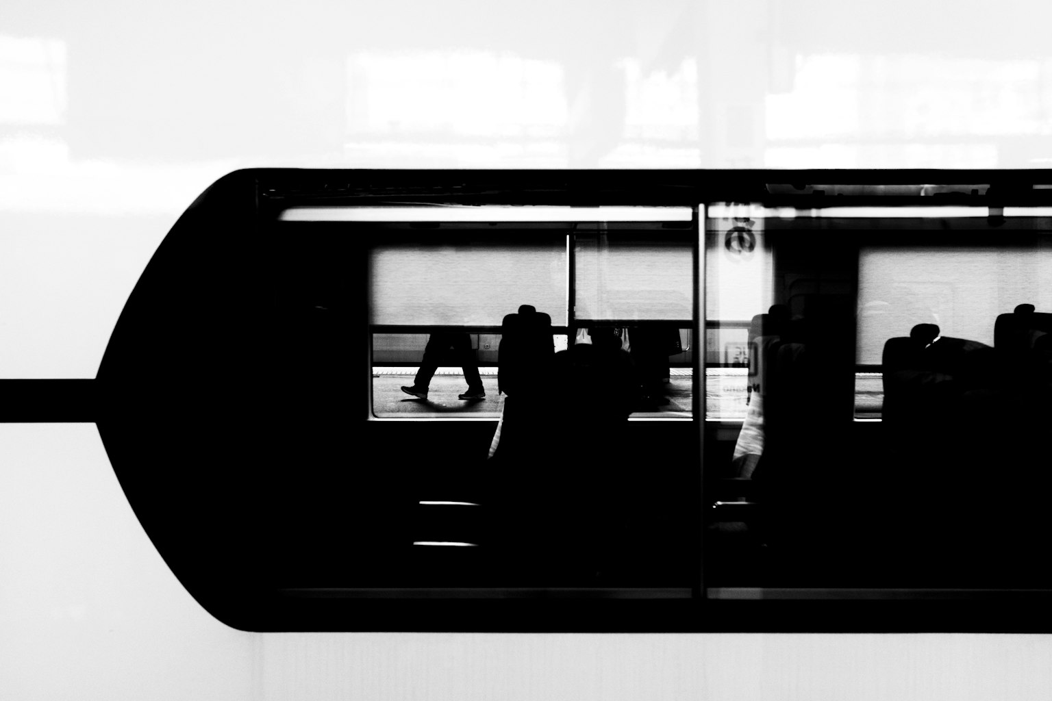 Silhouetten von Menschen durch ein schwarz-weißes Zugfenster gesehen