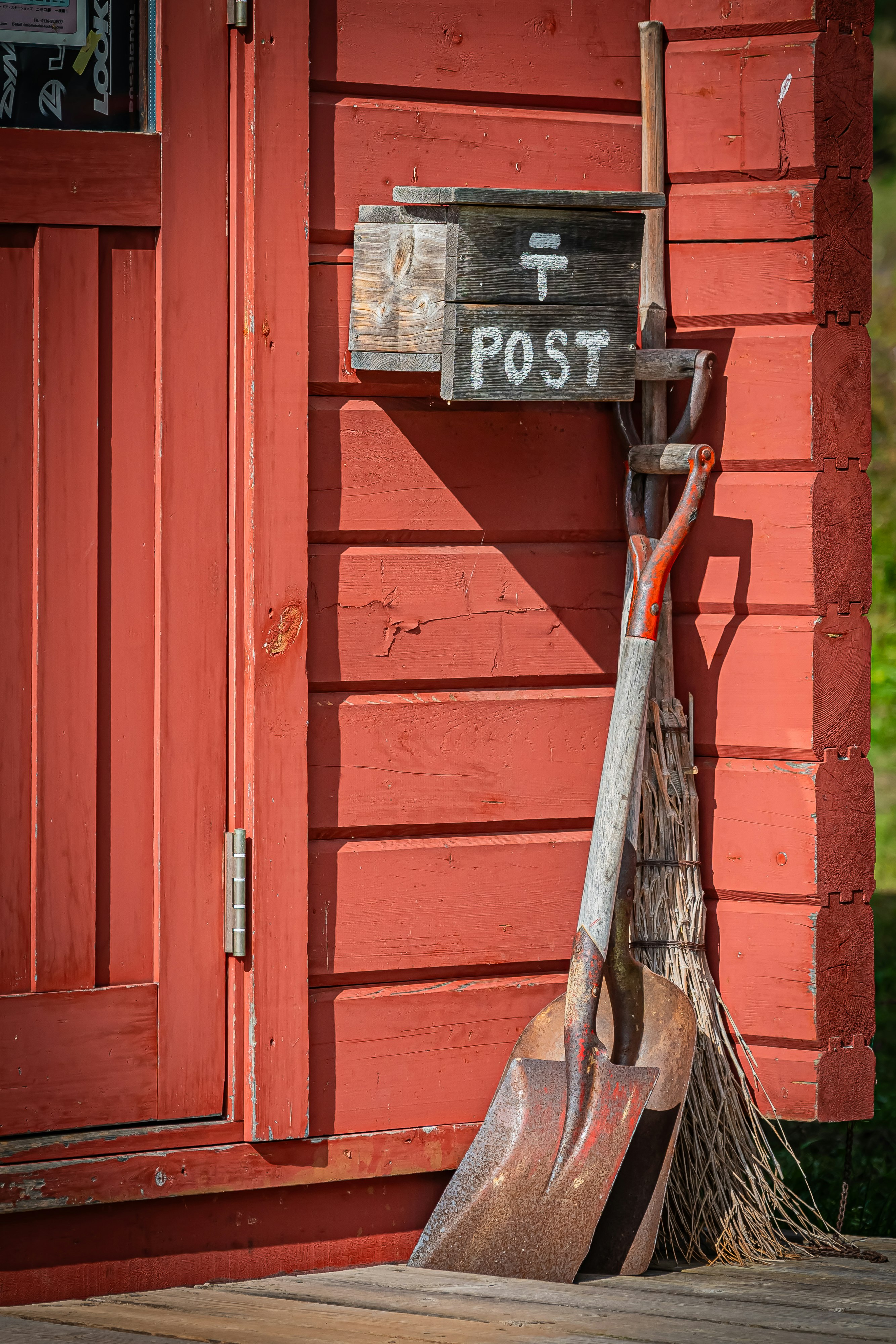 red mailbox and cleaning tools by an entryway wall