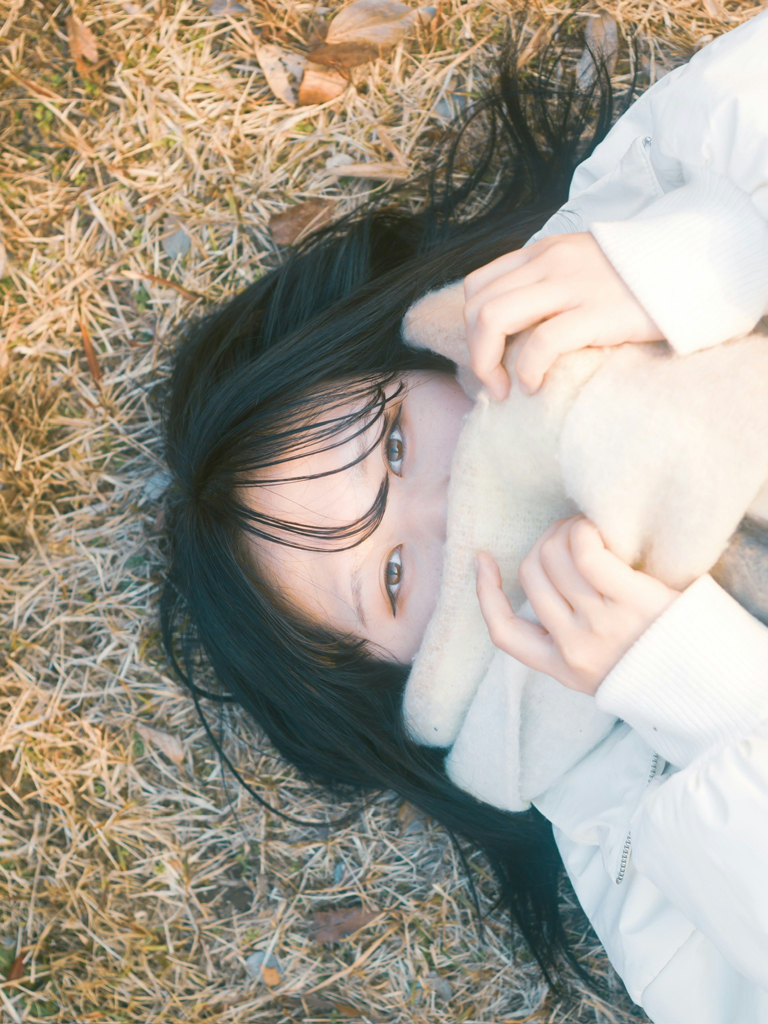 草むらで毛布に包まれた女性の寄り添う表情