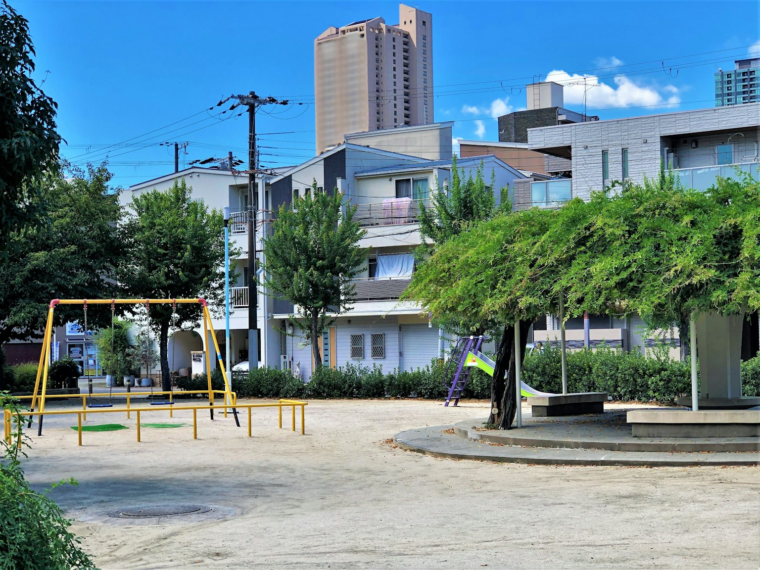 公园场景，秋千和滑梯，背景是高层建筑