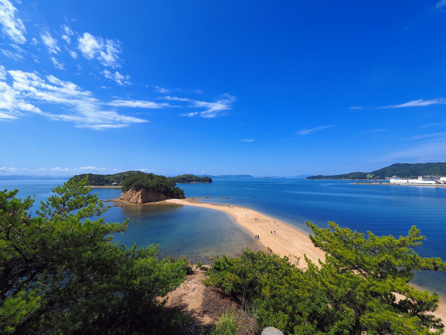 Pemandangan pantai berpasir yang dikelilingi langit biru dan lautan