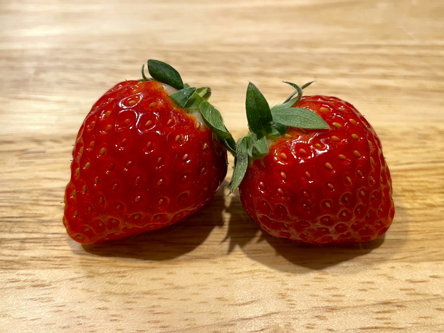 Zwei rote Erdbeeren auf einem Holztisch