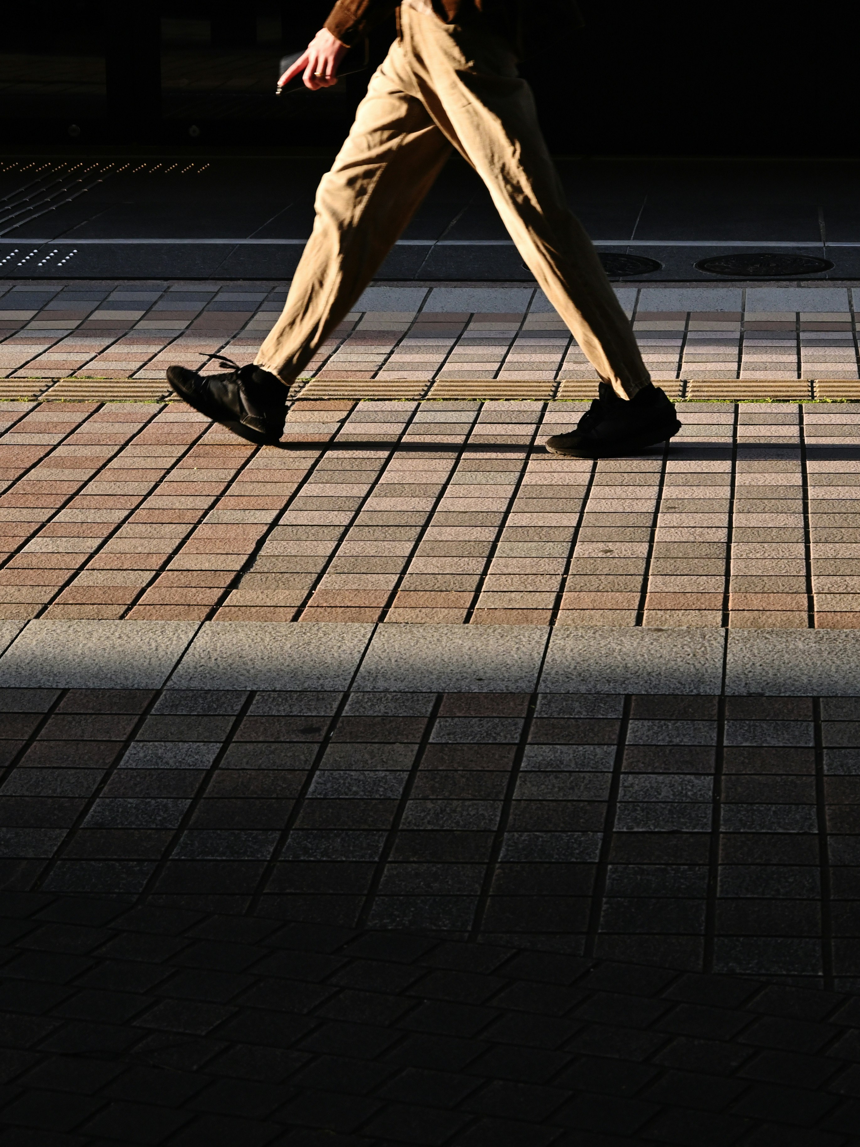 i piedi di una persona che cammina su una pavimentazione esterna a Sendai