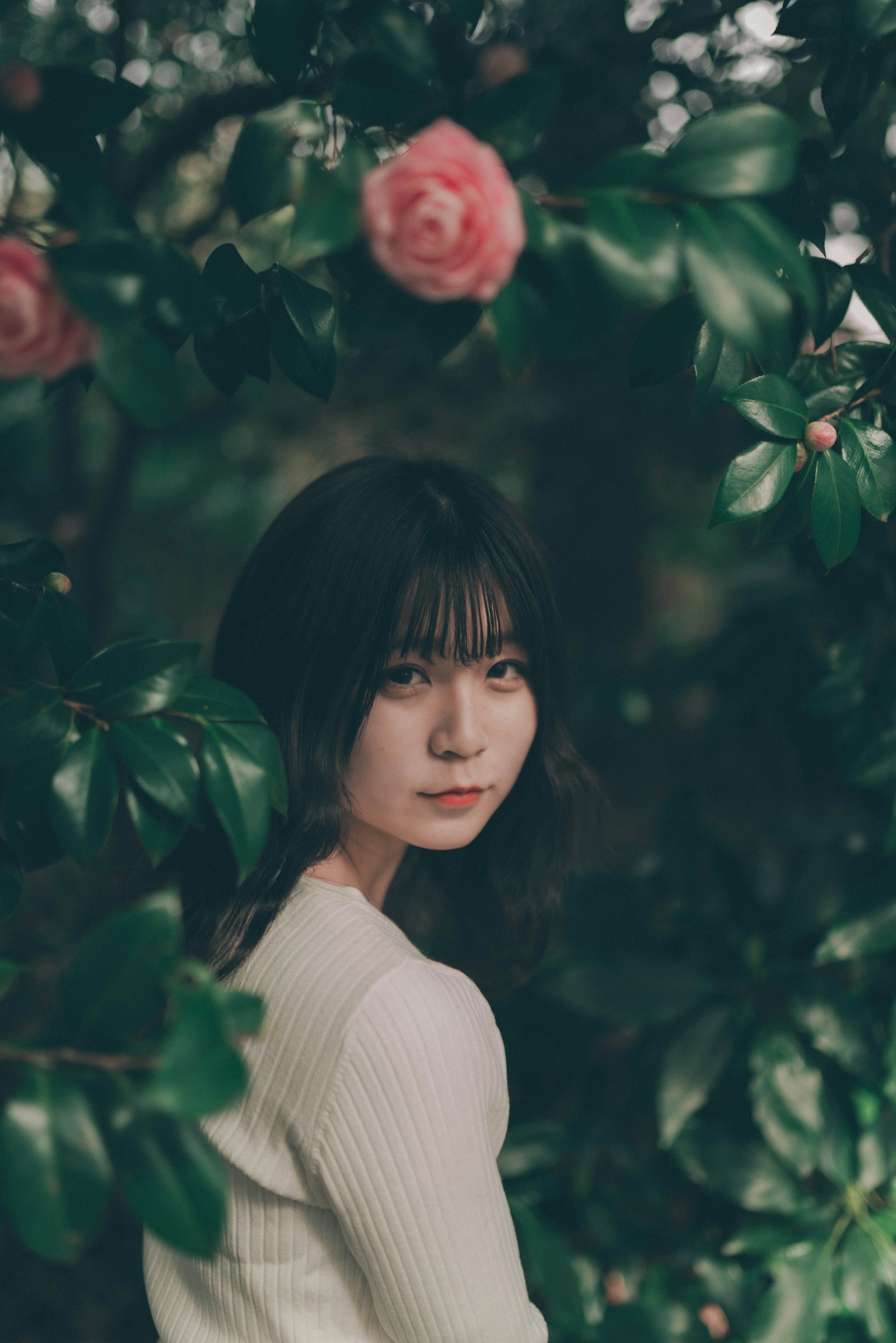 Portrait d'une femme entourée de feuilles vertes et de fleurs roses