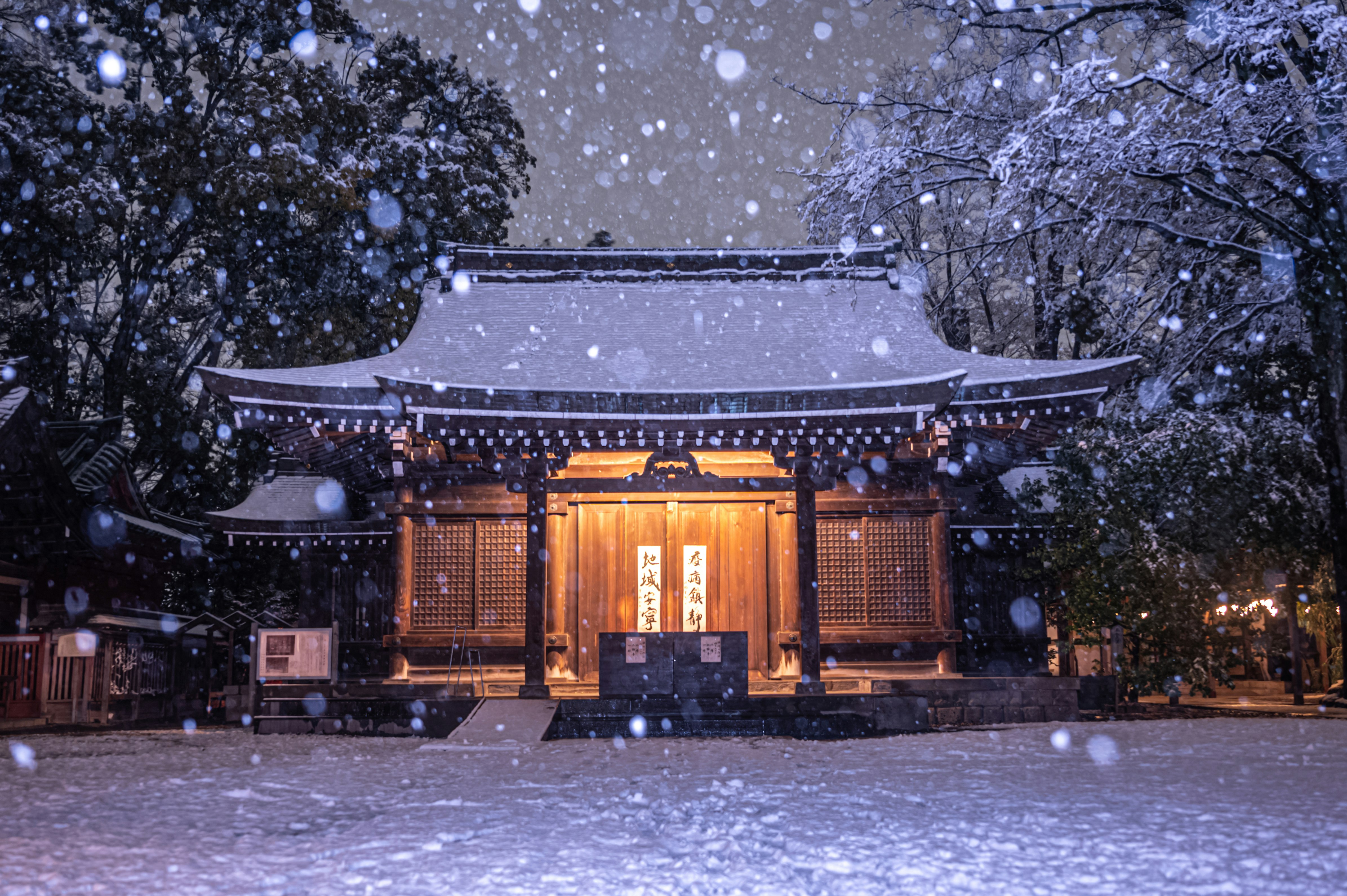 front view of a shrine with lantern lights in snowfall