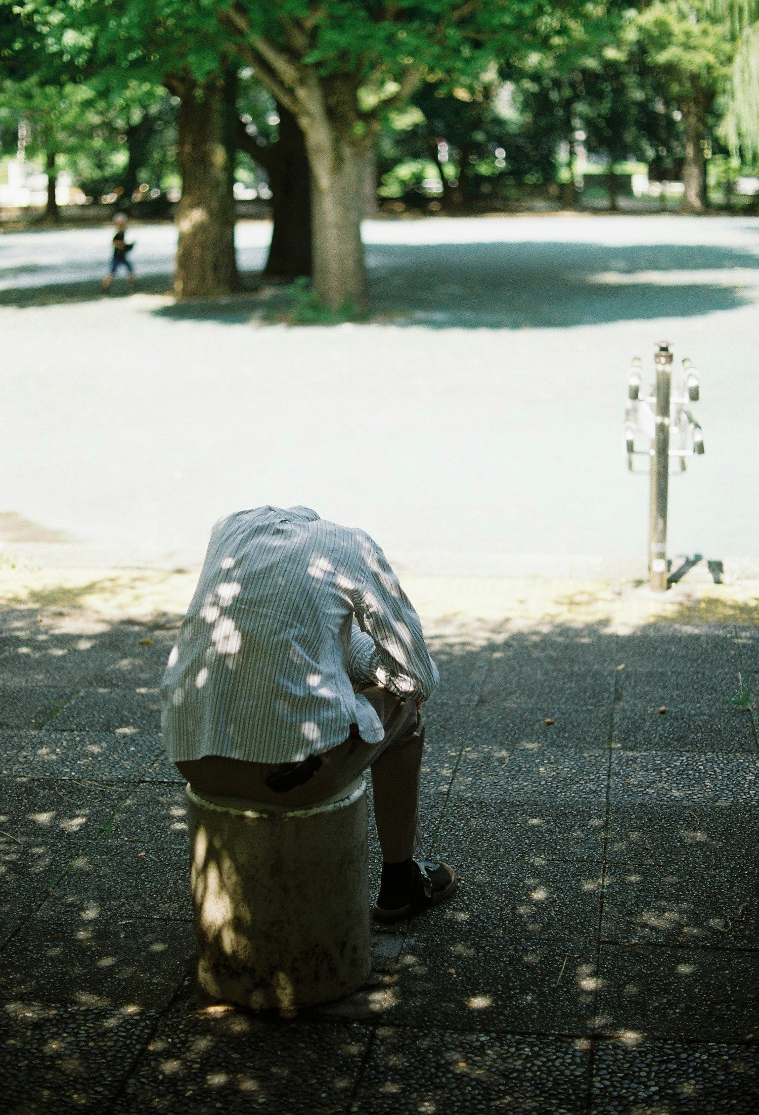 公園の木漏れ日の下で寝ている人