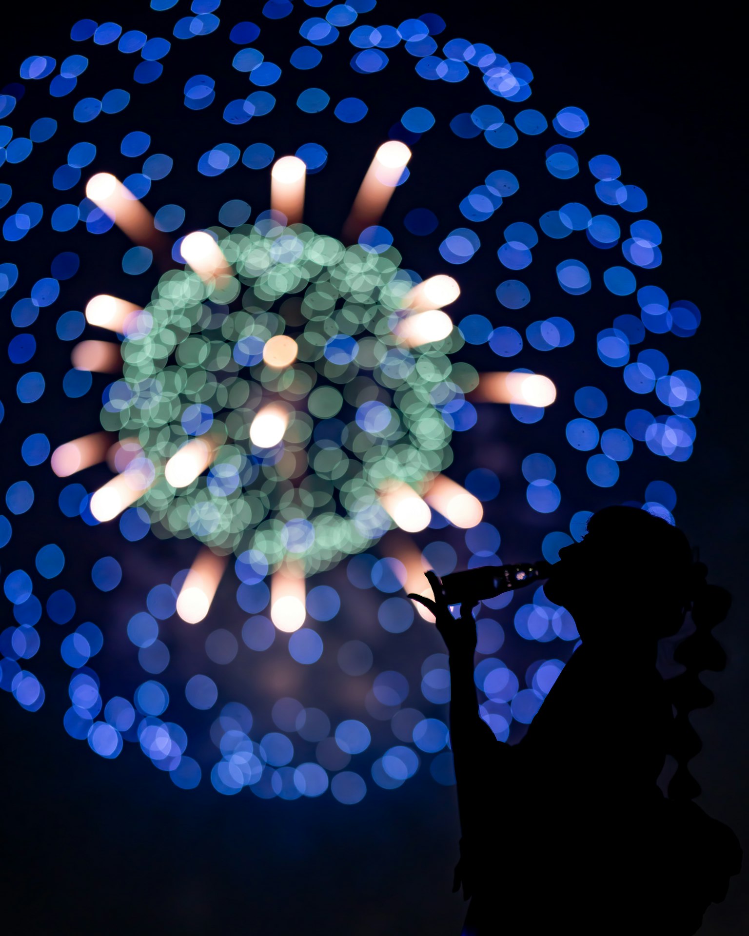 Silhouette di una persona che suona uno strumento contro fuochi d'artificio colorati