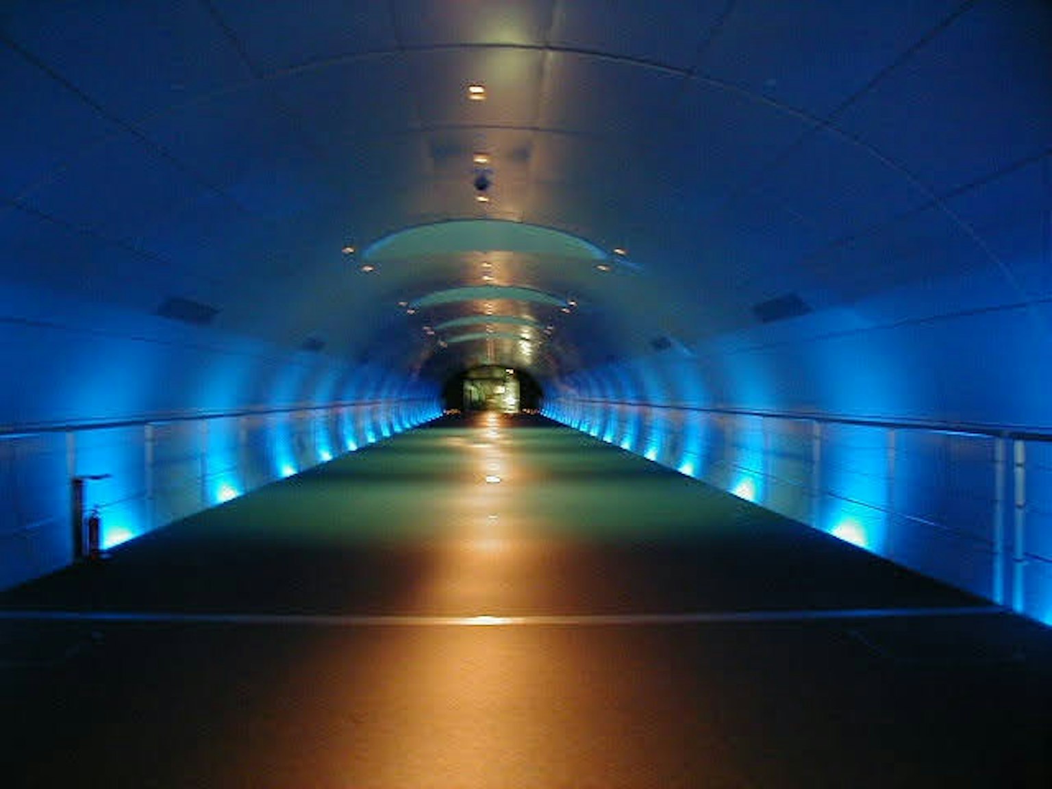 Interior de un largo túnel iluminado por luces azules