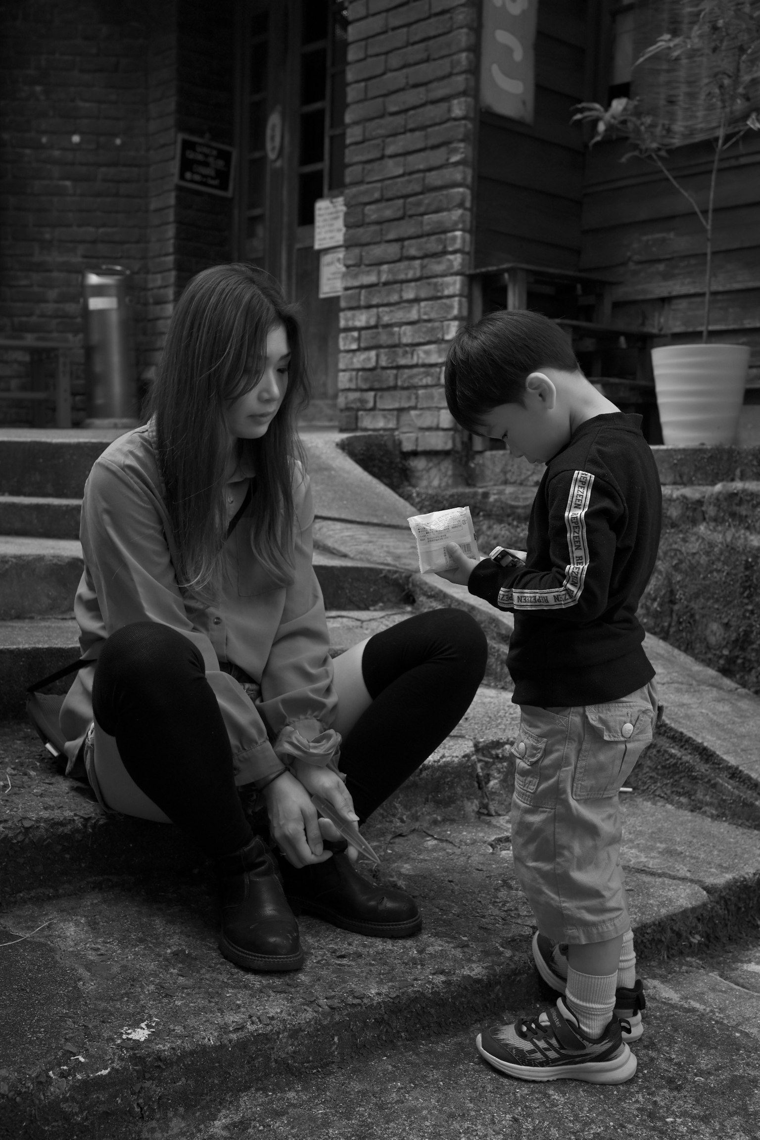 階段に座っている女性と子供のモノクロ写真