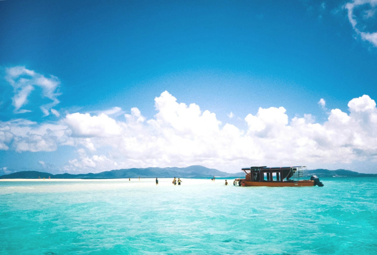 Vista panoramica di una piccola barca e persone su una bella spiaggia con acqua turchese e cielo blu