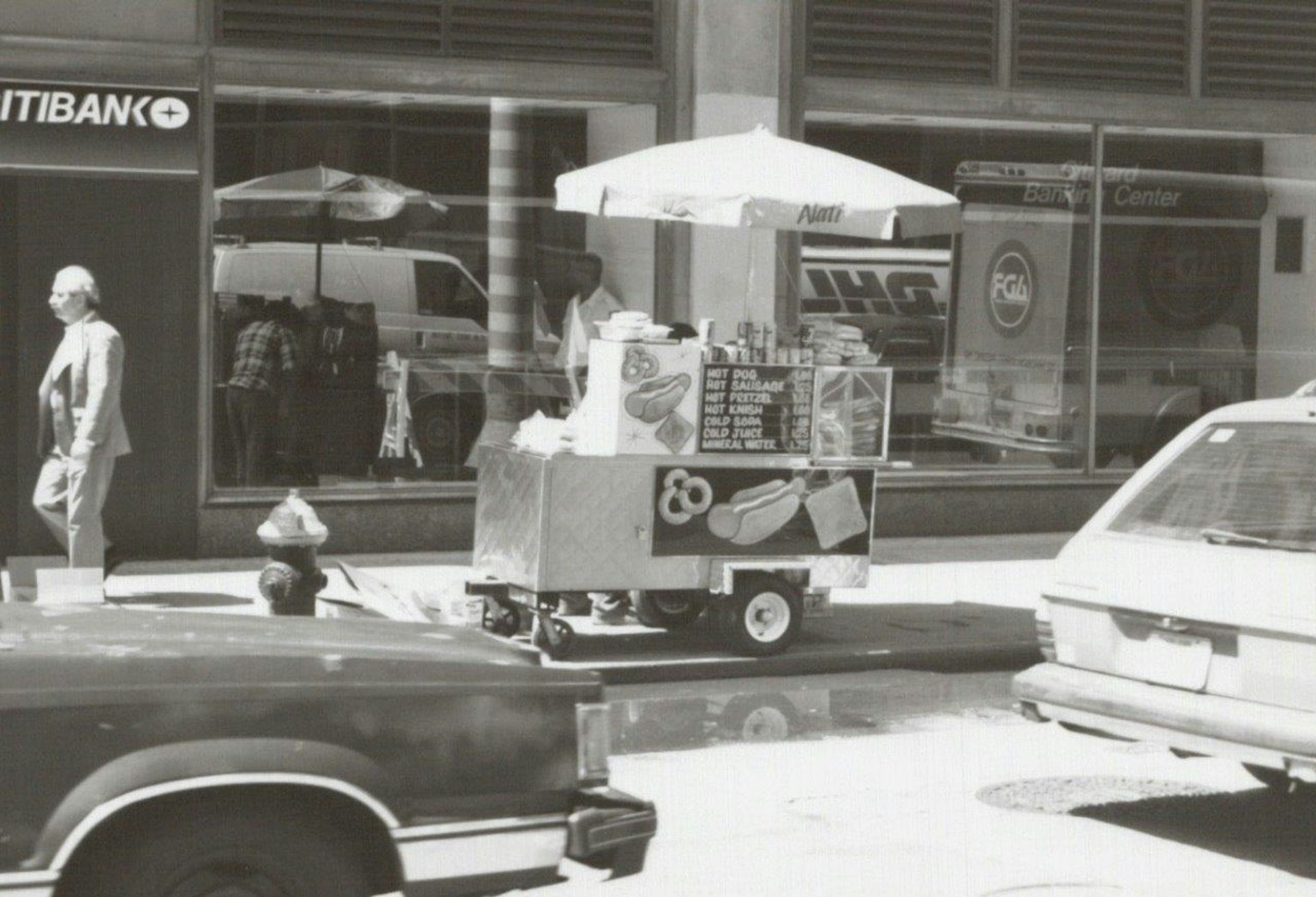 Carrello di cibo da strada con ombrello in un contesto urbano