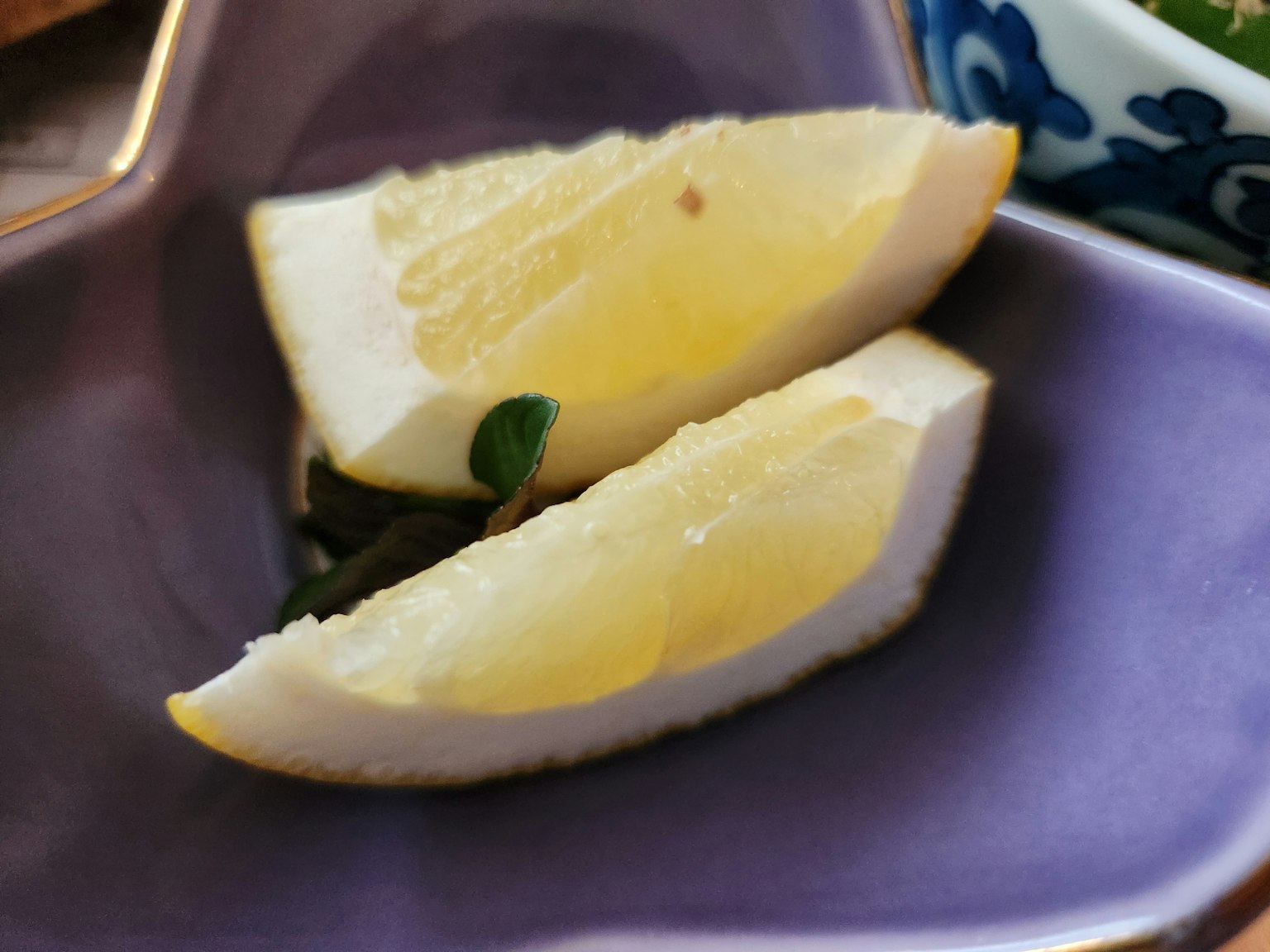 Zwei Zitronenscheiben auf einem lila Teller mit einem kleinen grünen Blatt