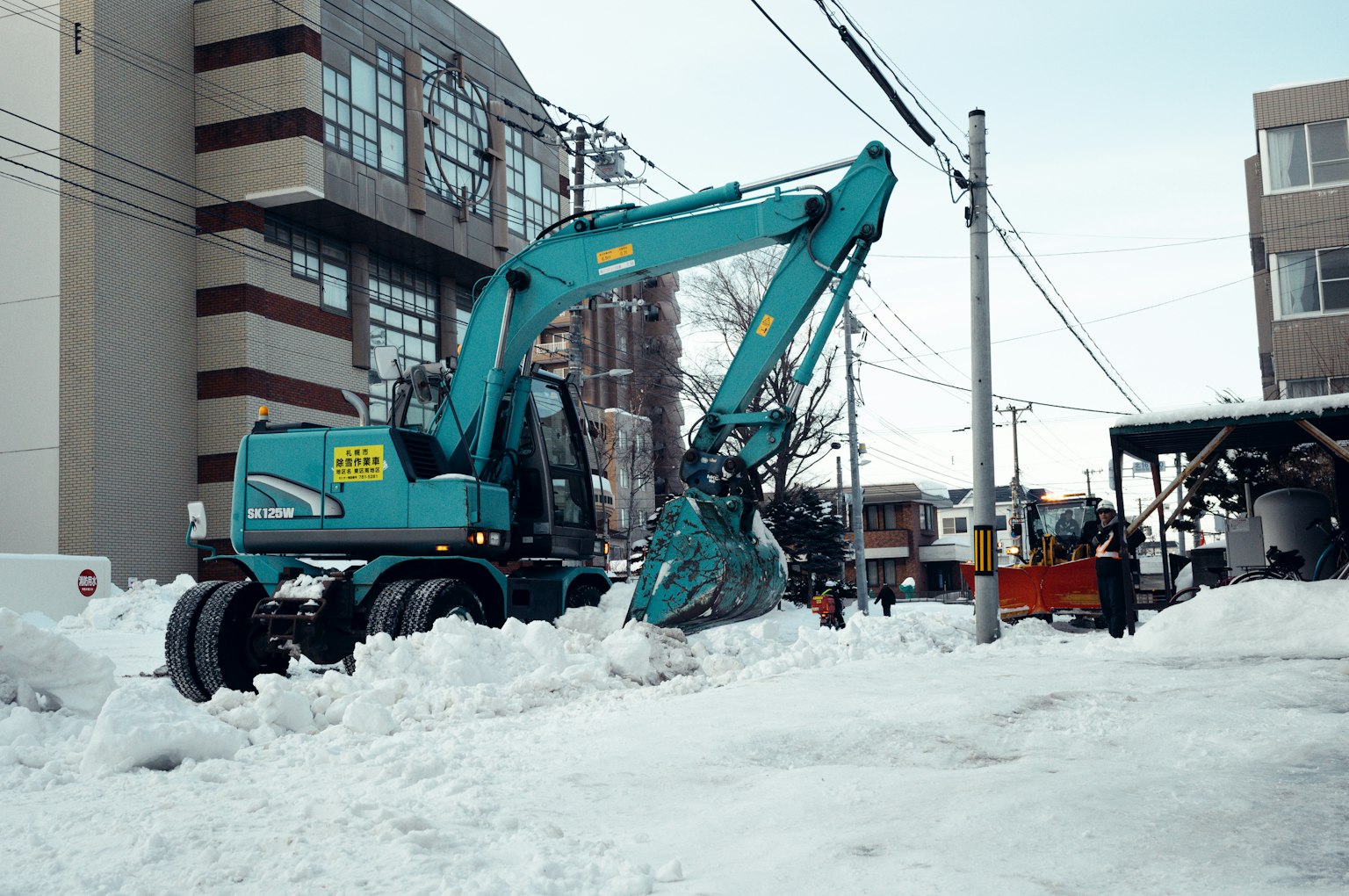 Excavatrice bleue déblayant la neige d'une rue