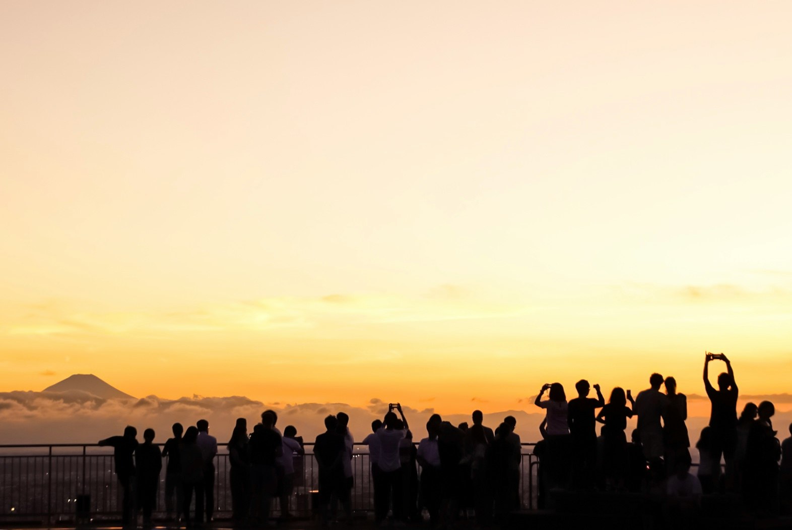 夕暮れの海辺でシルエットの人々が夕日を見つめる景色