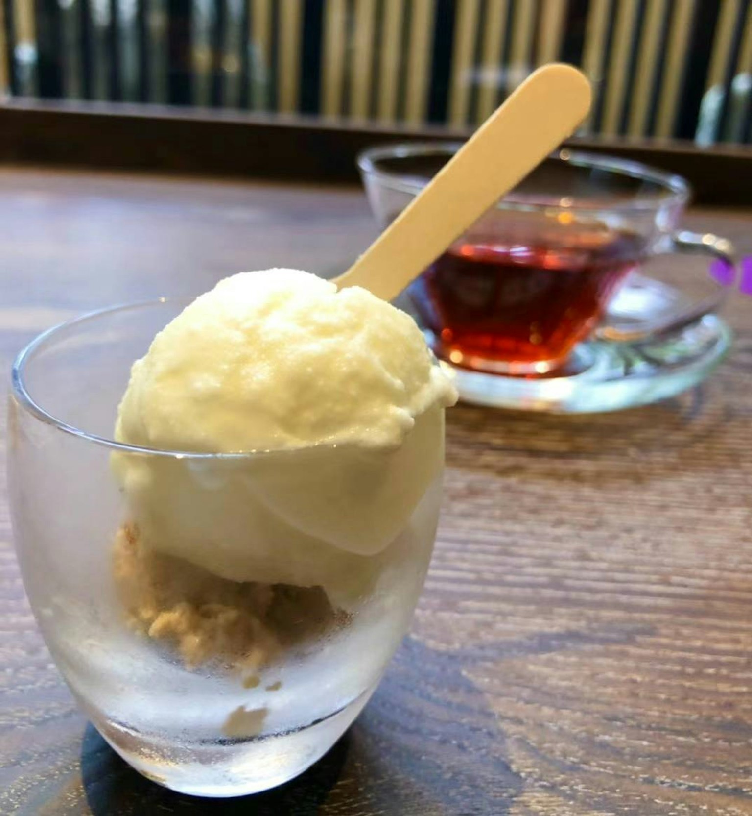 Cremige Eiscreme in einem klaren Glas mit einem Holzlöffel serviert