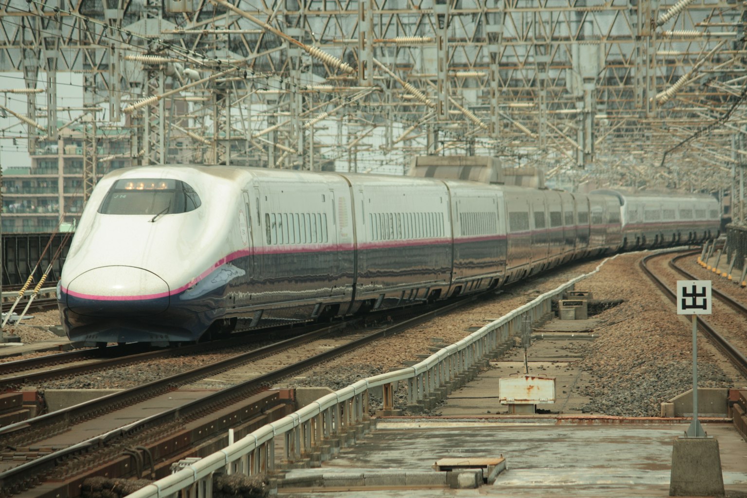 Treno Shinkansen su binari circondato da cavi aerei