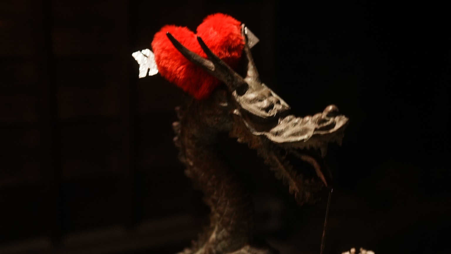 Sebuah patung naga dihiasi dengan dekorasi bunga merah di latar belakang gelap