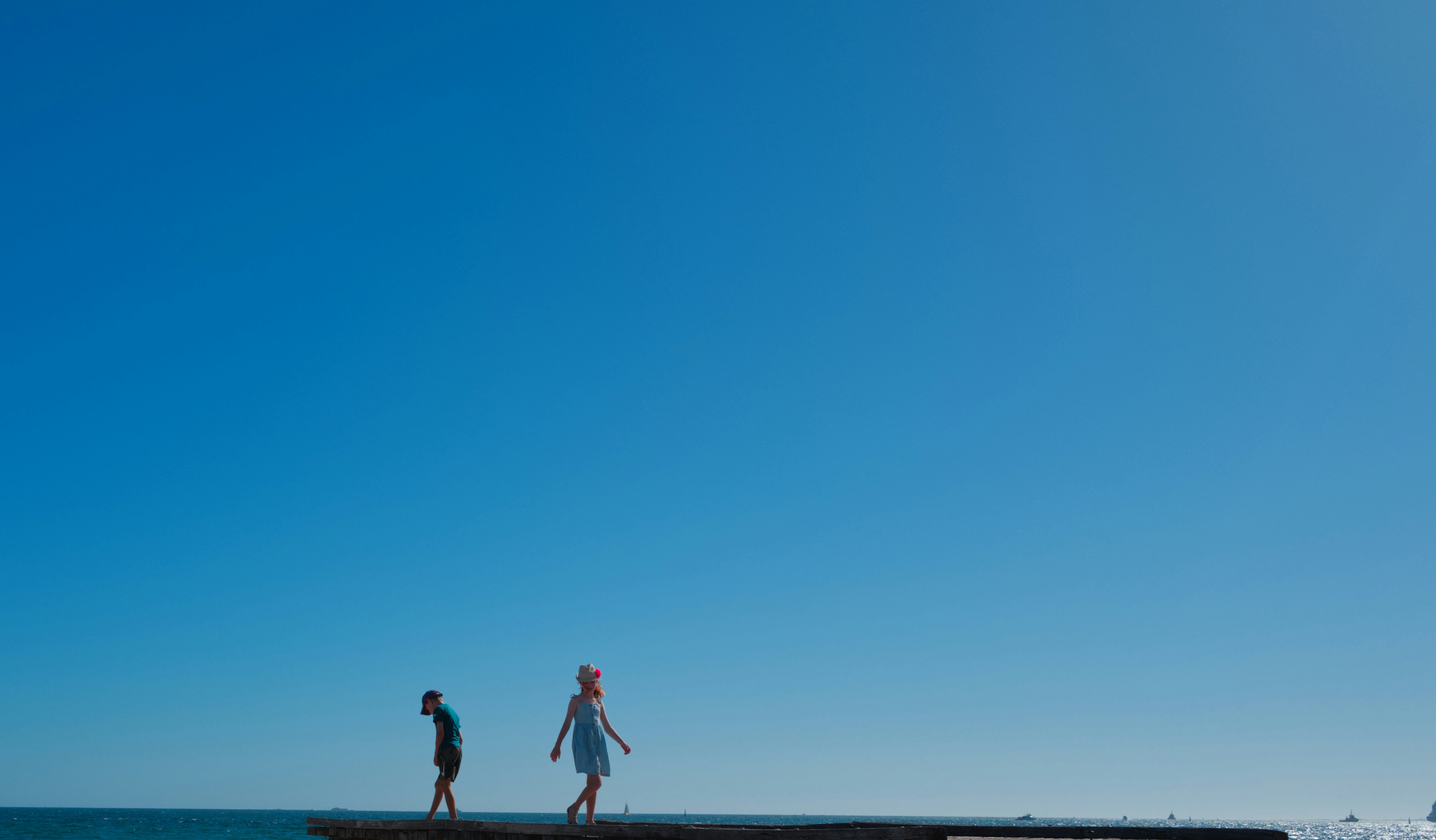 秋の澄んだ空の下、広がる海辺で歩く人々