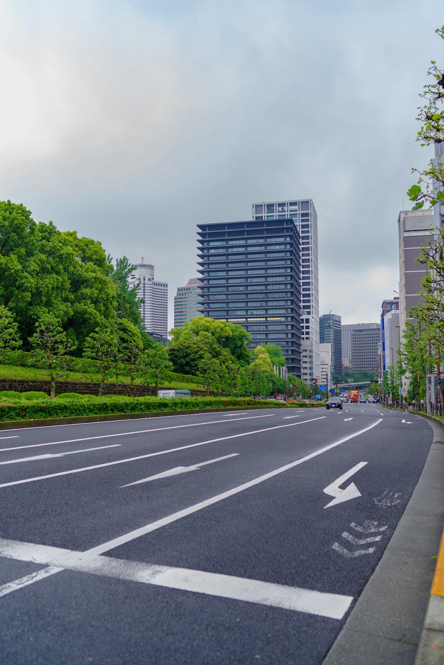 Scena urbana con strada, vegetazione rigogliosa e grattacieli