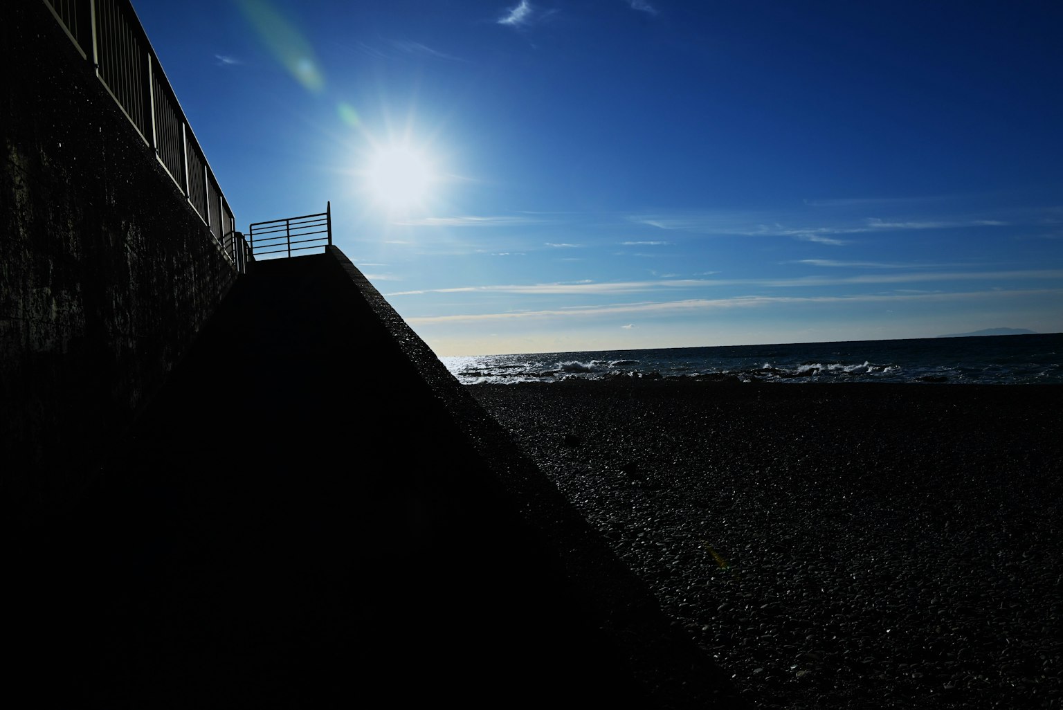 Silhouette einer Küste mit Sonnenlicht, das sich auf dem Meer spiegelt