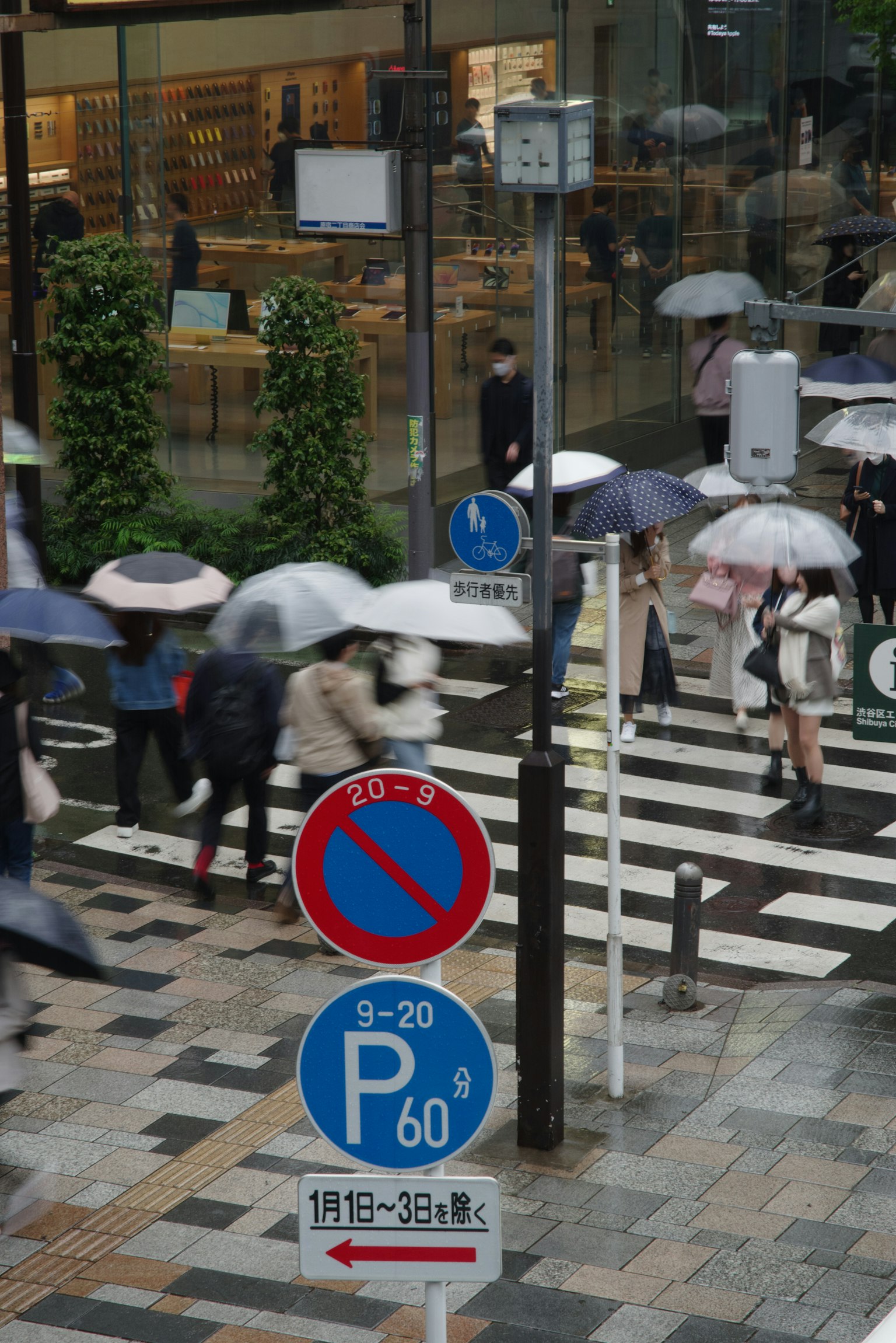 Street scene with pedestrians holding umbrellas and traffic signs in the rain