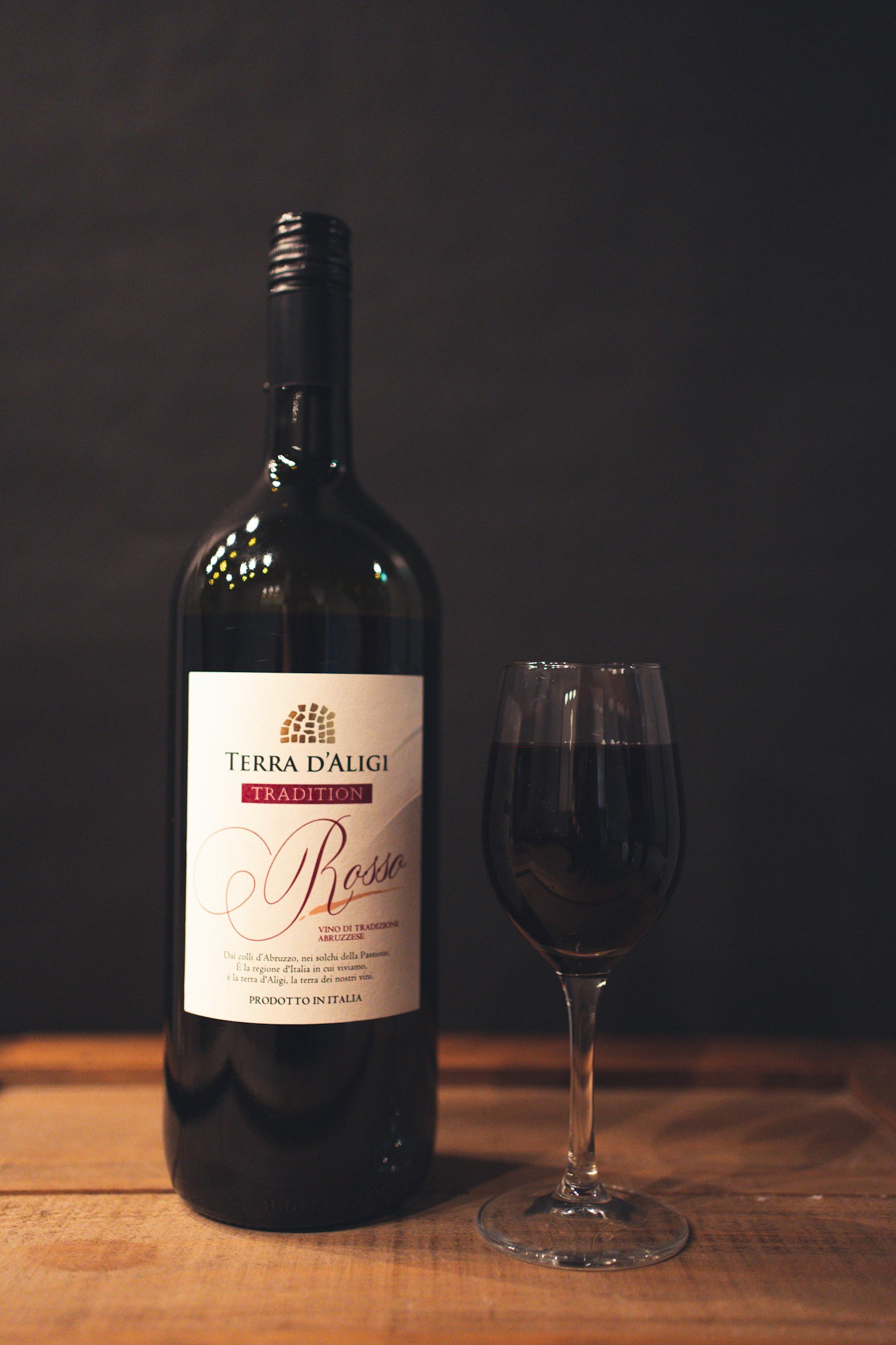 Une bouteille de vin rouge et un verre sur une table en bois