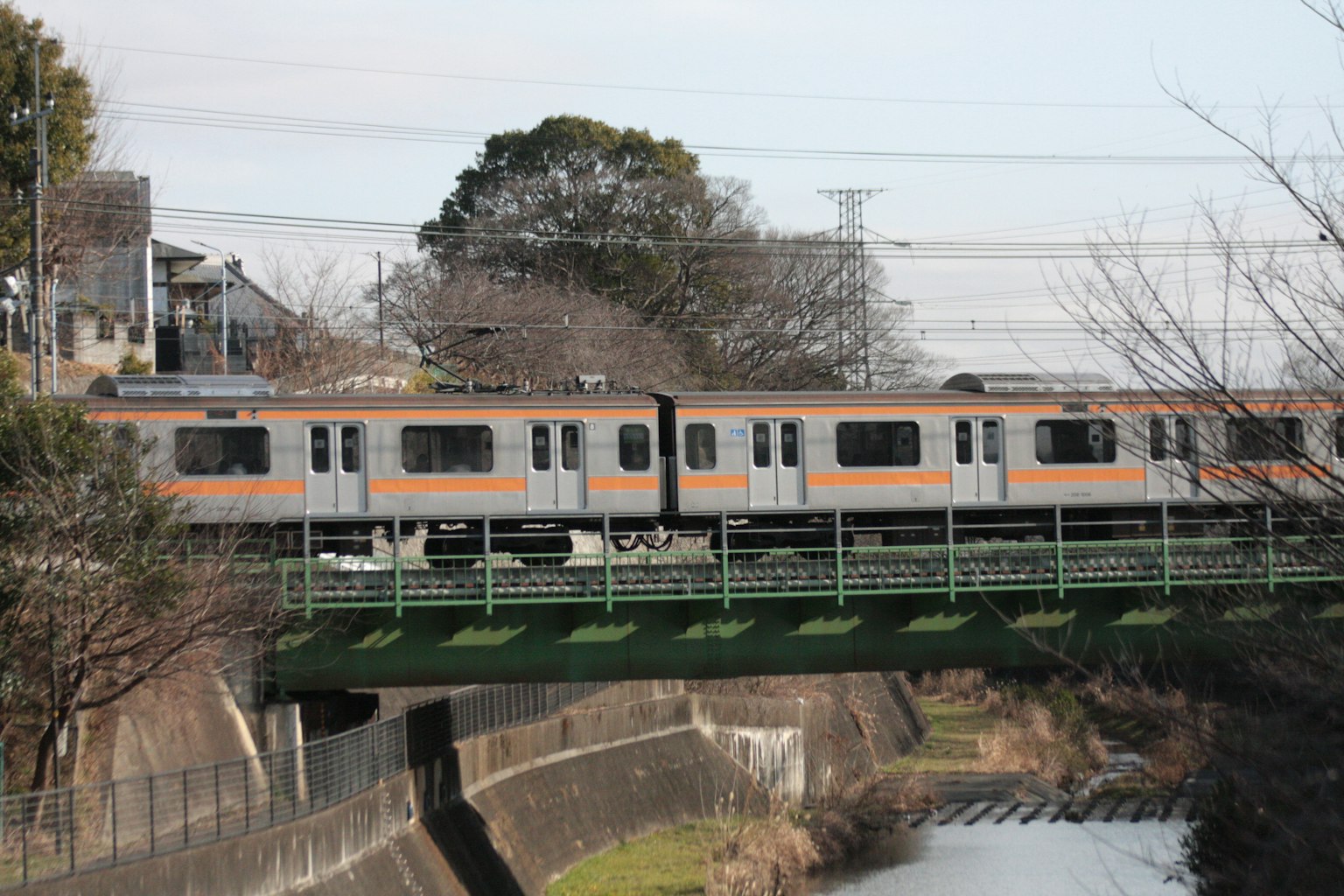 Train crossing a green bridge over a river