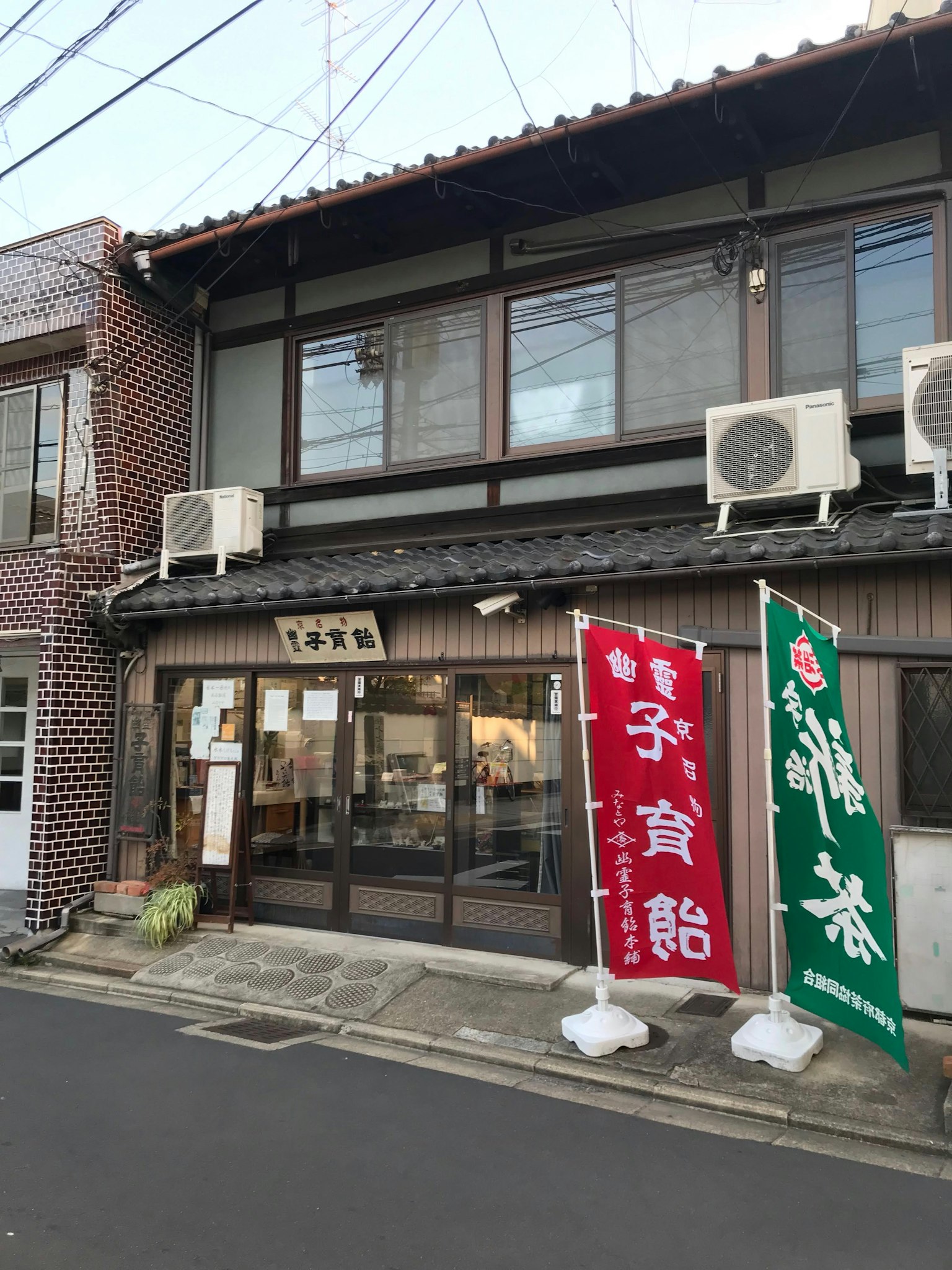 伝統的な日本の建物の外観に赤と緑ののれんが掛かっている
