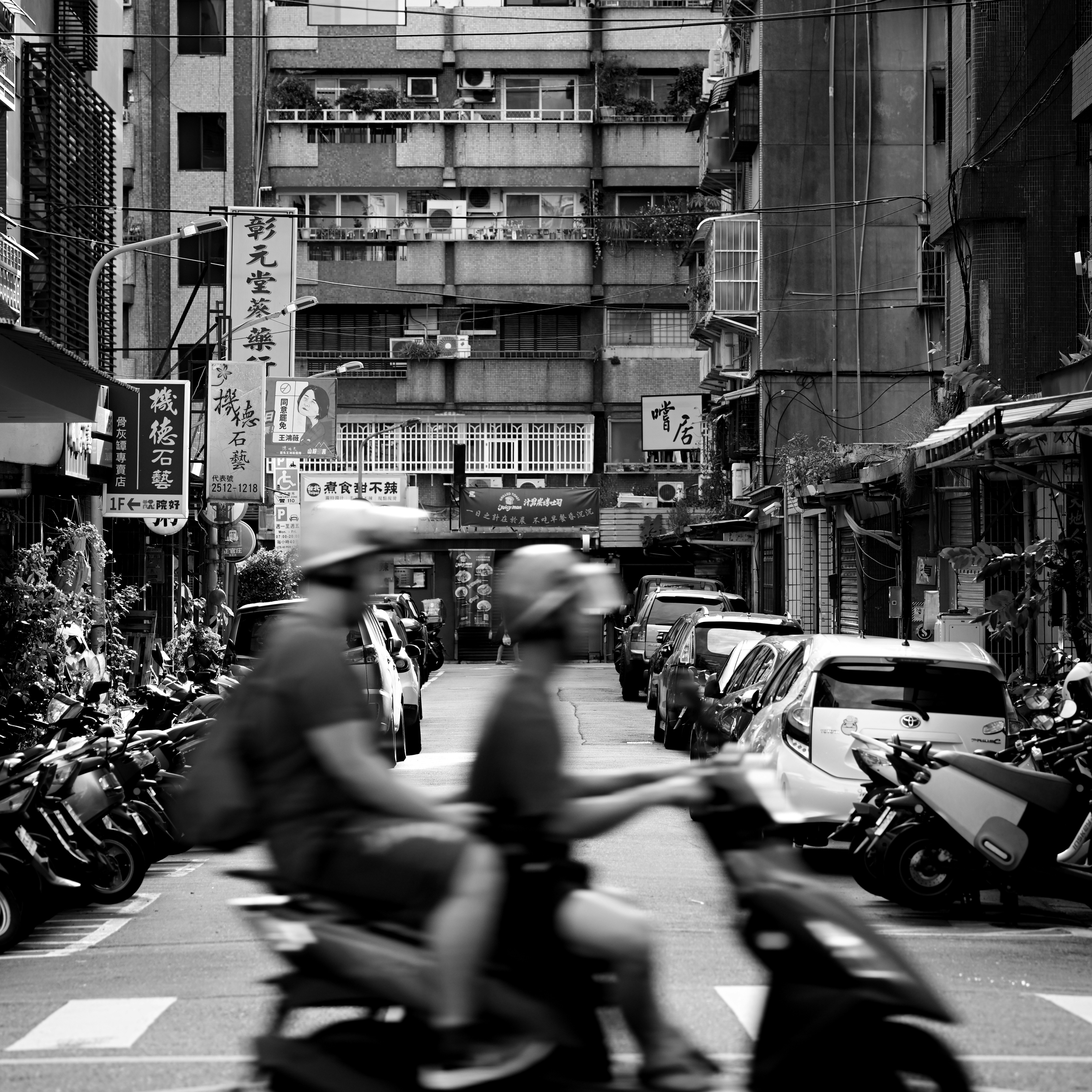 台北の路地を走るスクーターとバイクのある街並み