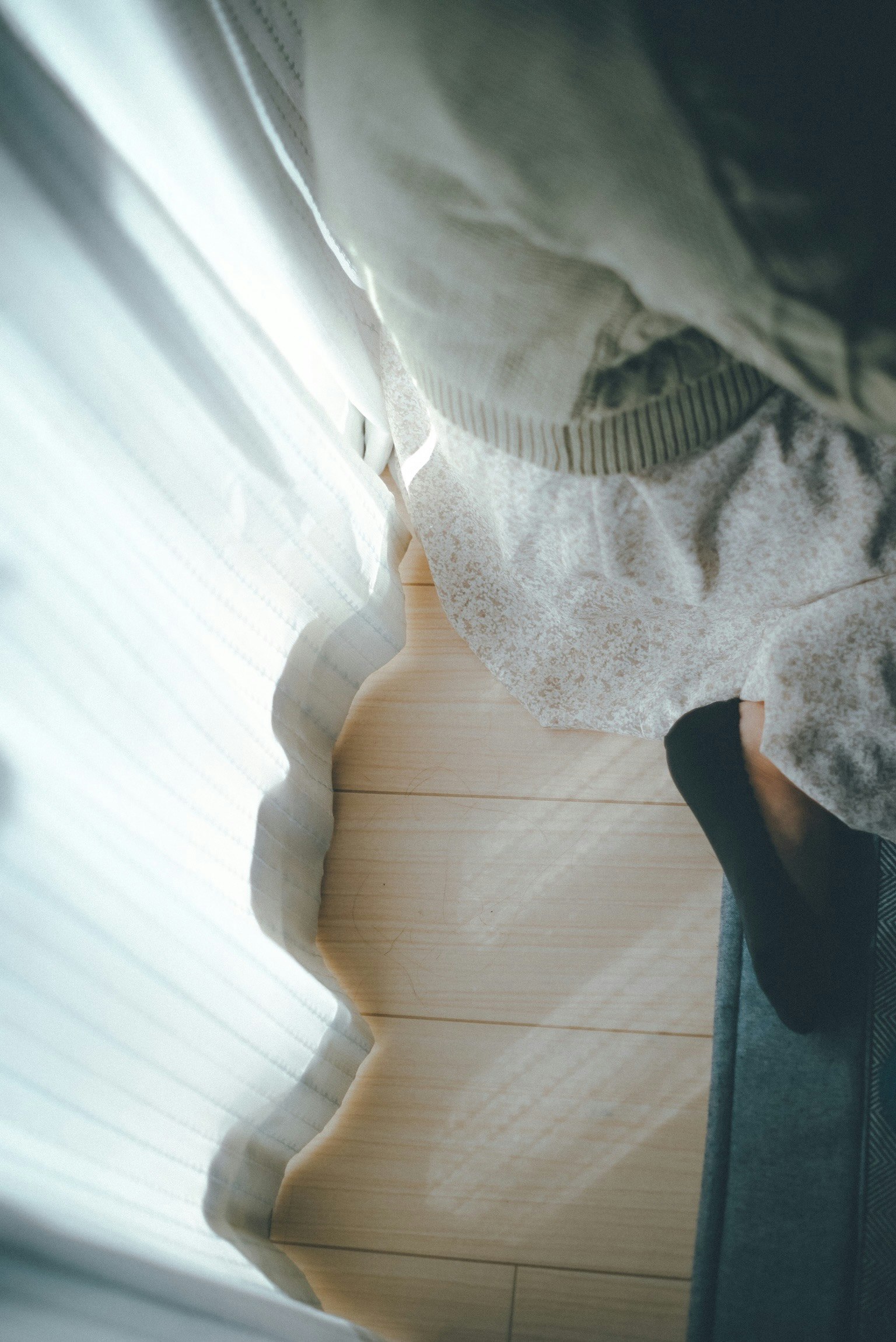 Luce che filtra attraverso una tenda con i piedi di una persona sul pavimento